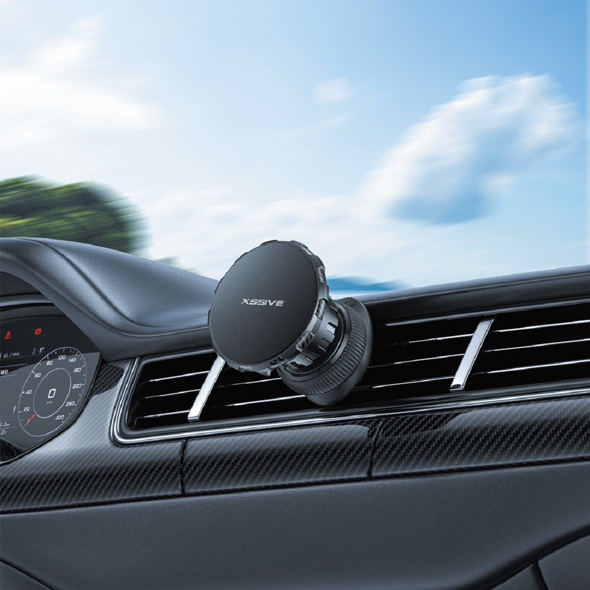 Een zwarte telefoonhouder voor in de auto is bevestigd aan een ventilatierooster. Het dashboard en een snelheidsmeter zijn zichtbaar. De lucht is blauw met wolken.