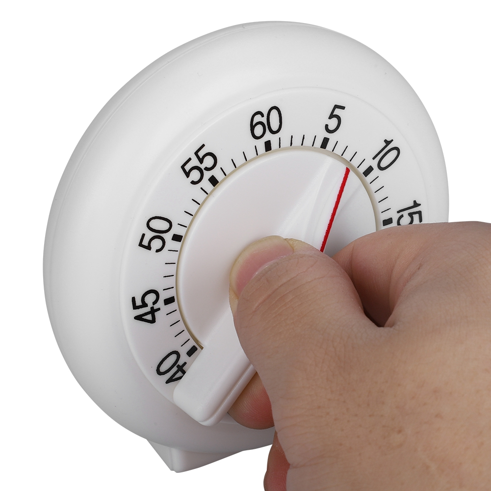 Ein weißer Küchentimer, der von einer Hand aufgezogen wird. Der Timer hat eine rote Linie, die auf die Zeit zeigt. Auf dem Timer sind Zahlen gedruckt.