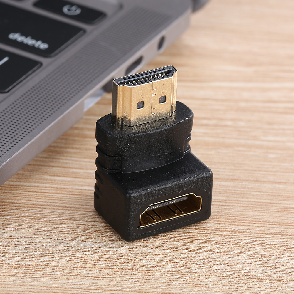 Schwarzer HDMI-Adapter auf Holzoberfläche. Eine Laptop-Tastatur ist im Hintergrund. Der Adapter ist abgewinkelt, goldene Anschlüsse sichtbar.