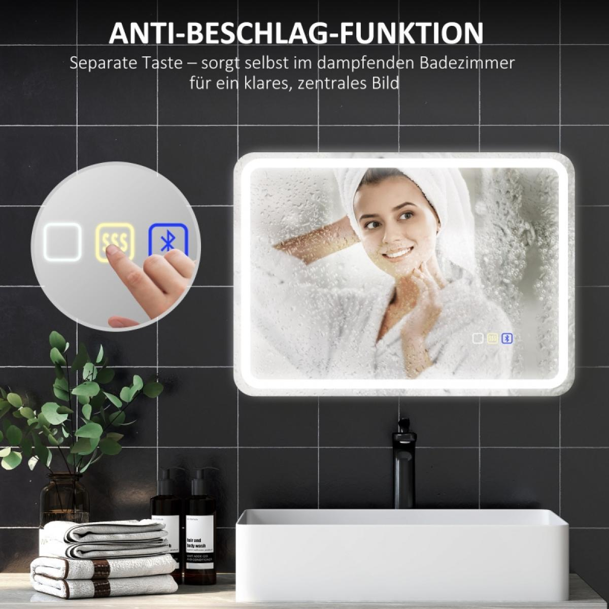 Eine Frau im Bademantel lächelt in einem Spiegel. Knöpfe sind links. Handtücher, Pflanzen und Flaschen stehen auf der Theke unter dem Spiegel.