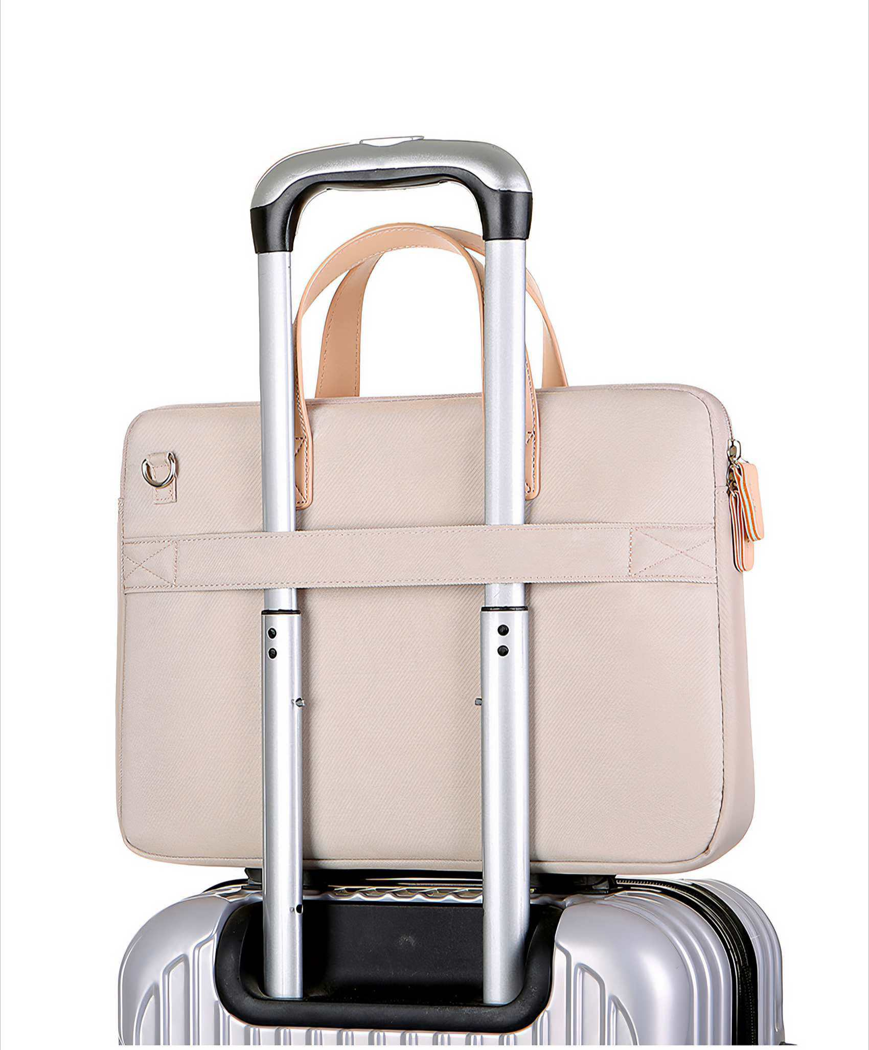 Eine hellbeige Laptoptasche auf einem silbernen Koffer. Die Griffe sind hochgeklappt. Der Hintergrund ist weiß.