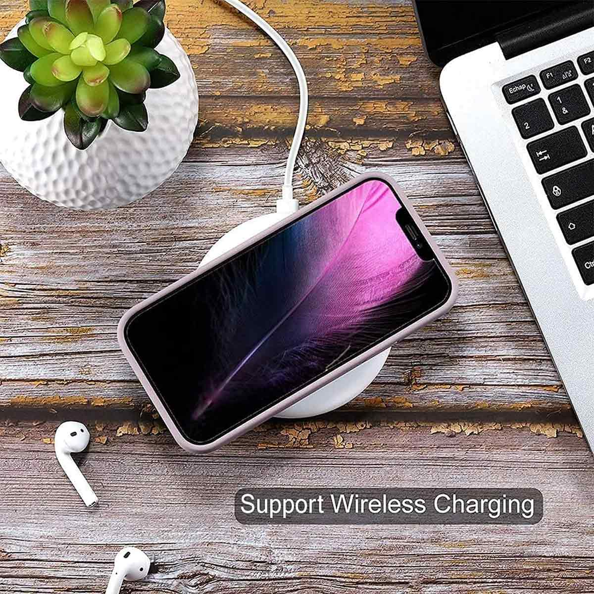 Telefon wird kabellos geladen, neben einem Laptop. Eine Pflanze in einem weißen Topf befindet sich oben. AirPods liegen auf der Holzoberfläche.