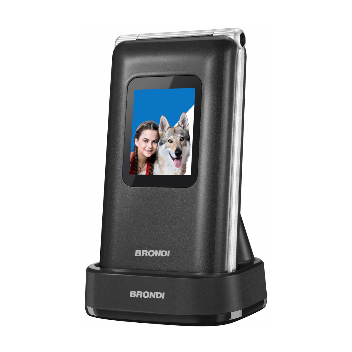Un teléfono plegable negro sobre una base de carga. La pantalla muestra una niña y un perro lobo. La marca es BRONDI.