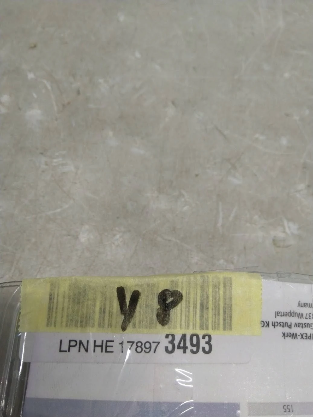 A barcode label on a package is visible. It has handwritten numbers. The background is light gray.