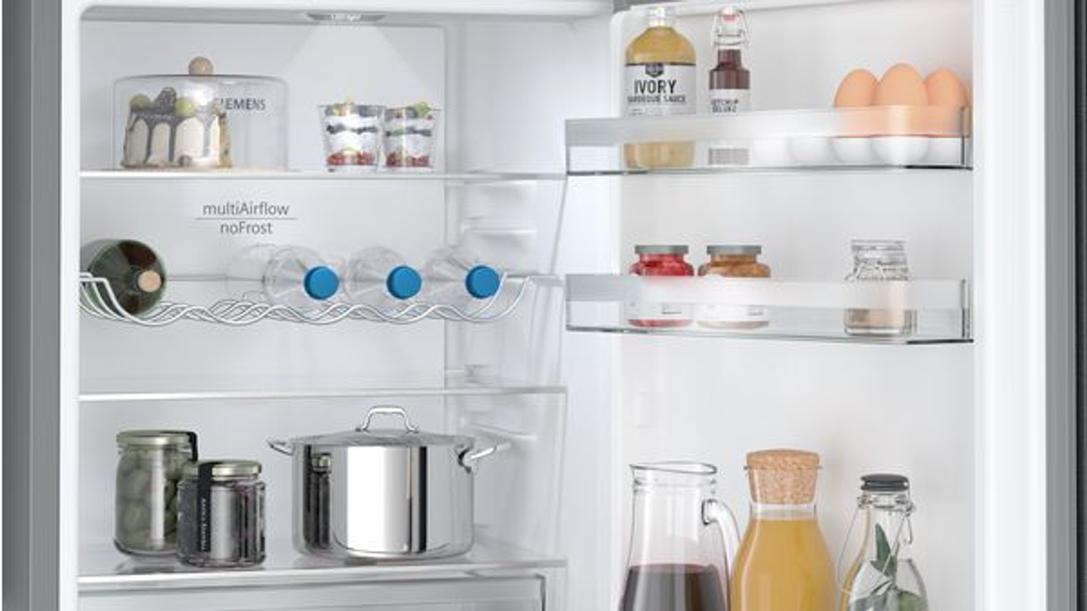 In einem Kühlschrank: Kuchen, Getränke, Eier, Gläser, ein Topf und Flaschen sind auf den Regalen sichtbar. Der Kühlschrank ist sauber und gut organisiert.