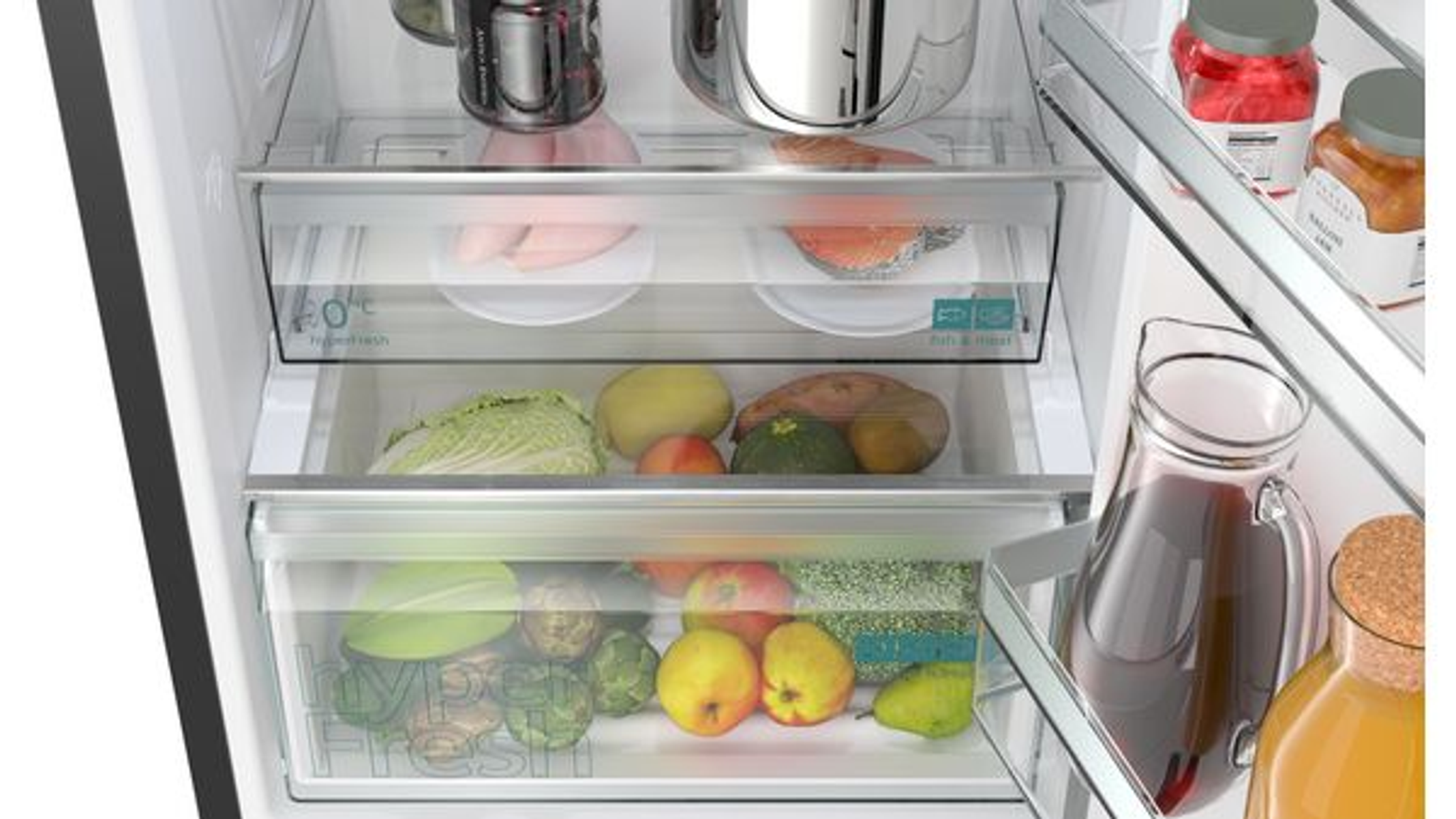 In einem Kühlschrank: Fleisch, Fisch und Gemüse werden in Schubladen aufbewahrt. Gläser, eine Saftkanne und ein Topf sind sichtbar.
