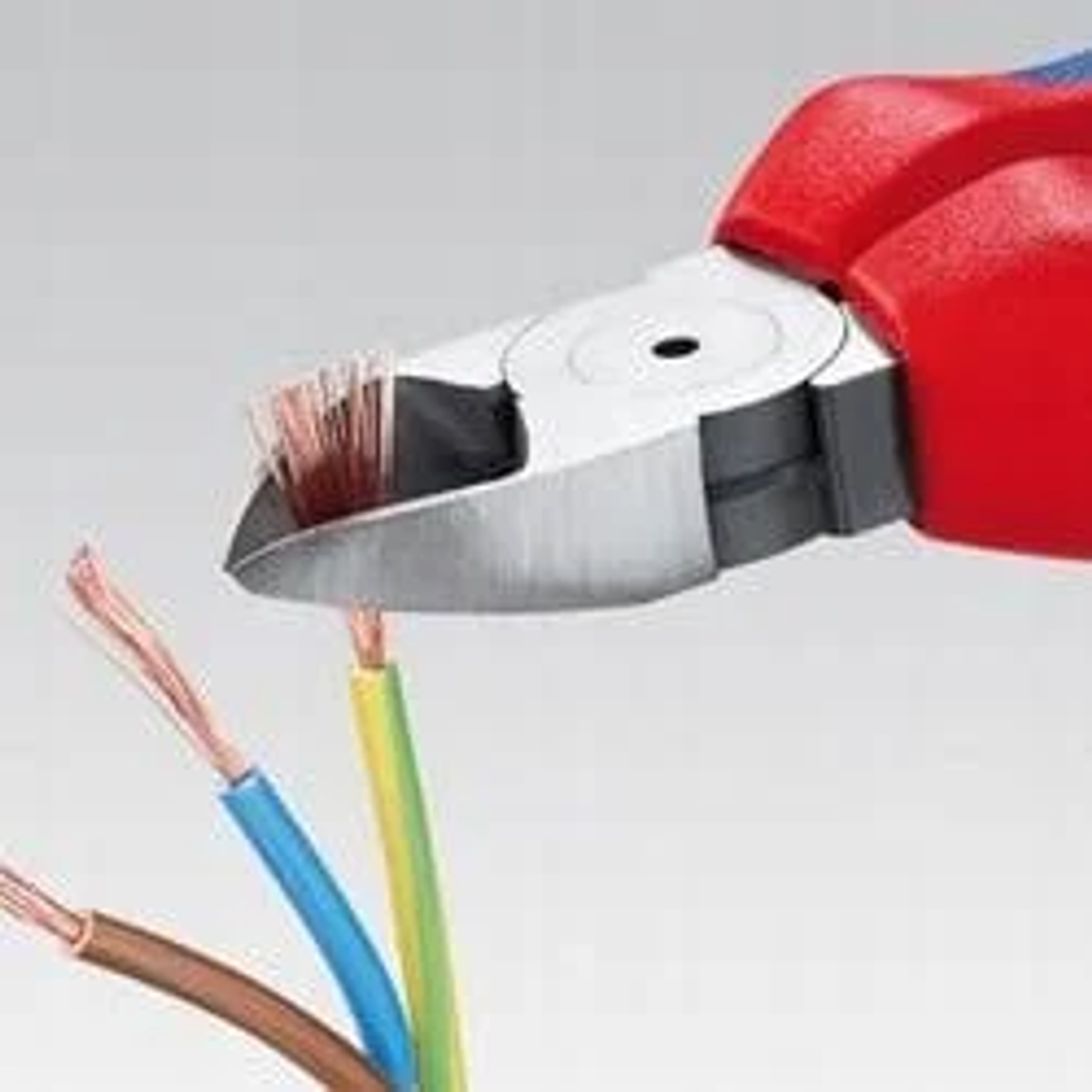 Szczypce do cięcia przewodów elektrycznych. Czerwono-niebieskie szczypce ze srebrnymi ostrzami. Przewody są brązowe, niebieskie i żółte.