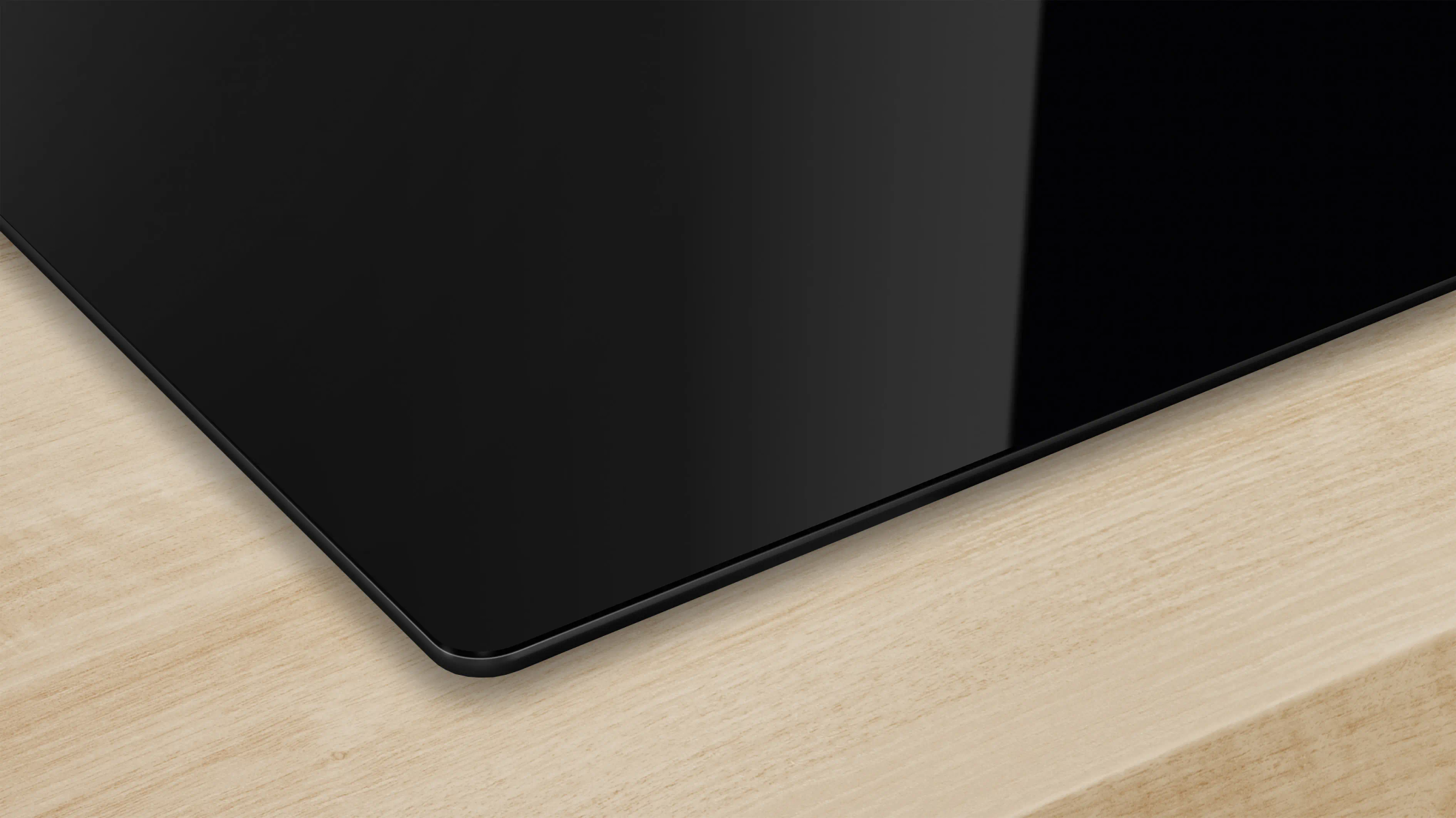 Una encimera negra y rectangular descansa sobre una superficie de madera clara. La encimera refleja la luz, creando brillo.