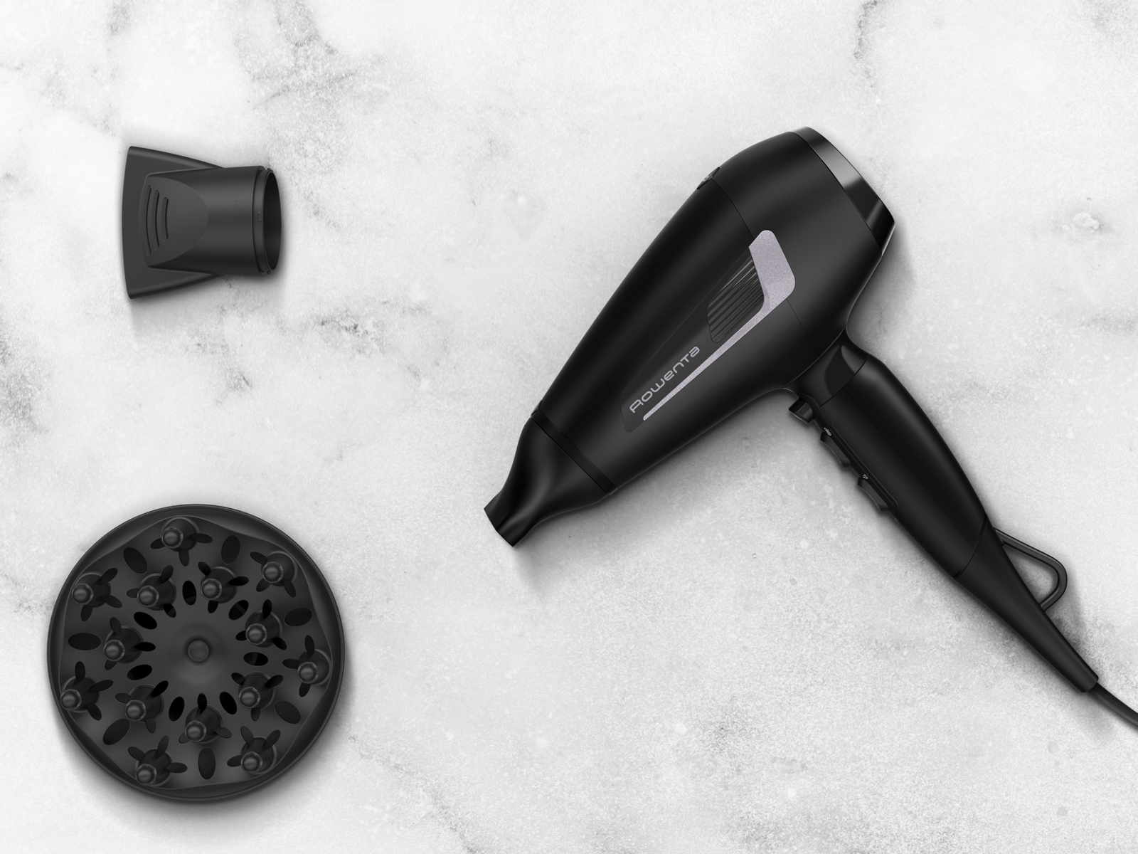 Czarna suszarka do włosów z nasadkami na marmurowej powierzchni. Akcesoria obejmują dyszę i dyfuzor. Suszarka ma markę Rowenta.