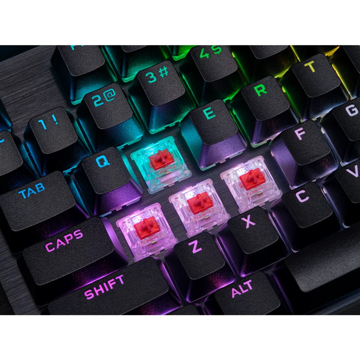 Primer plano de un teclado mecánico. Teclas negras con letras y números iluminados. Interruptores rojos visibles. Luces LED coloridas.