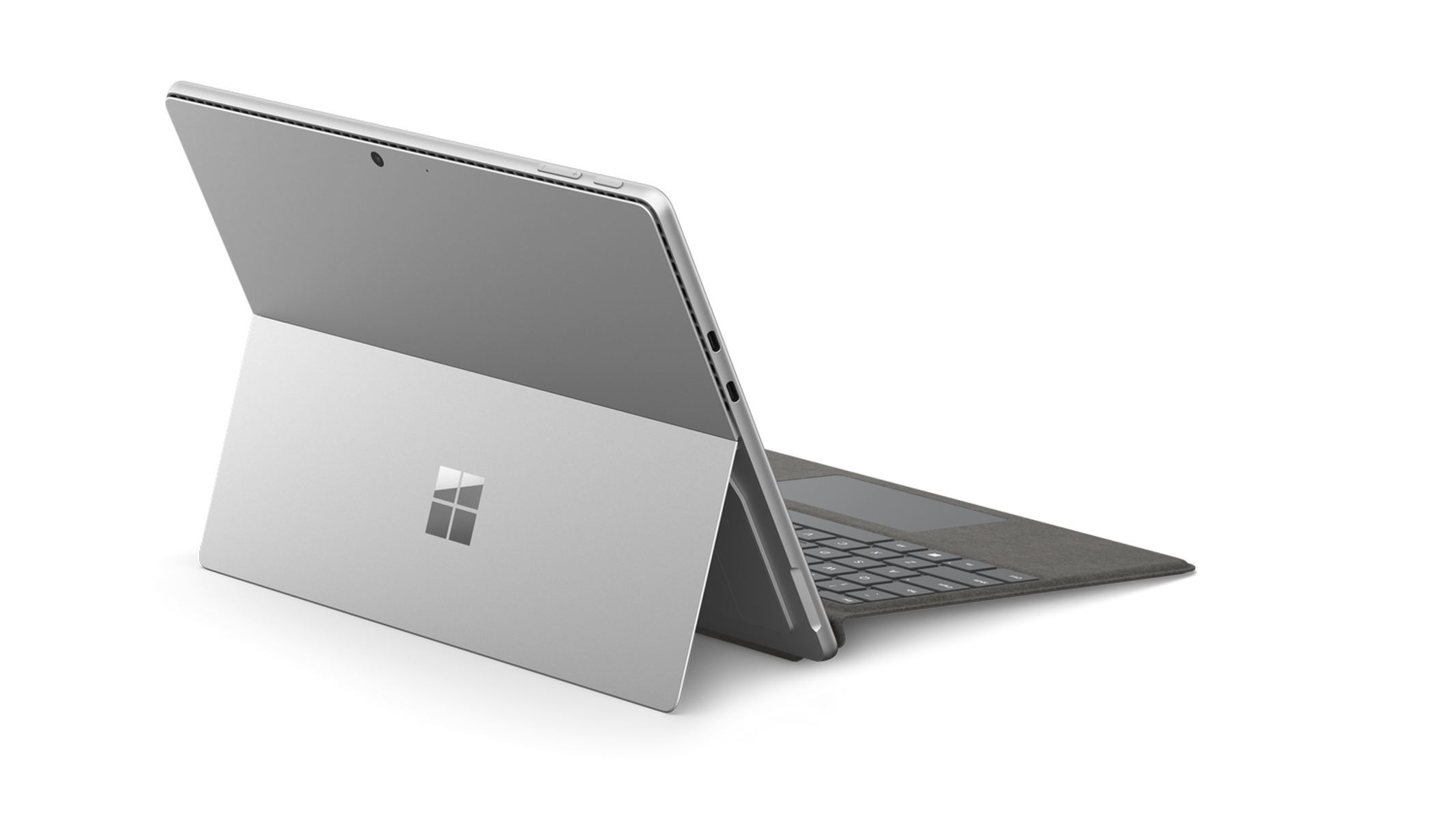 Srebrny laptop Microsoft Surface jest otwarty. Ekran jest ustawiony pod kątem, ukazując klawiaturę i logo Microsoft.