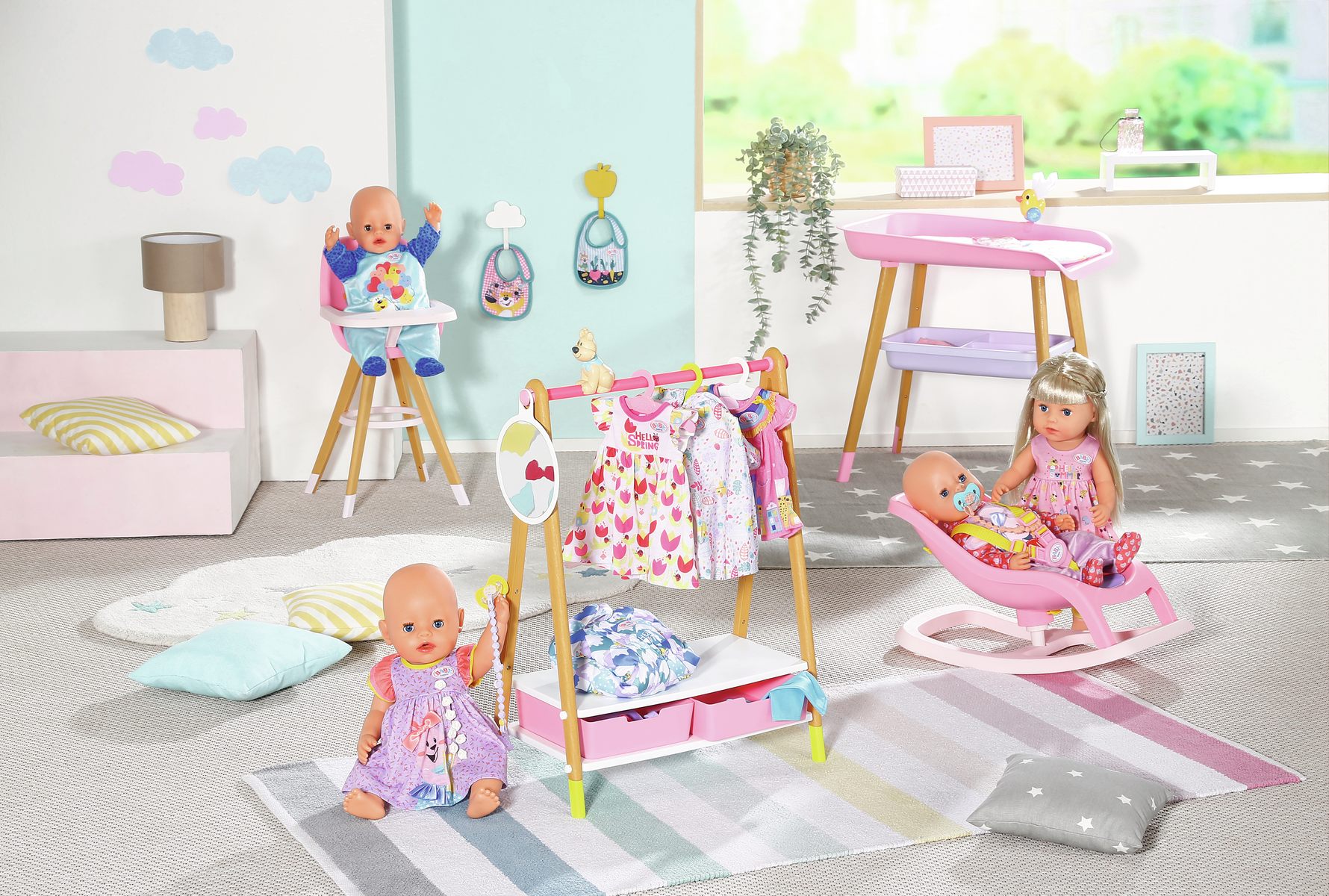 Una escena de sala de juegos con muñecas y accesorios para bebés, incluyendo una trona, un armario y un cambiador. Hay varios vestidos y juguetes.
