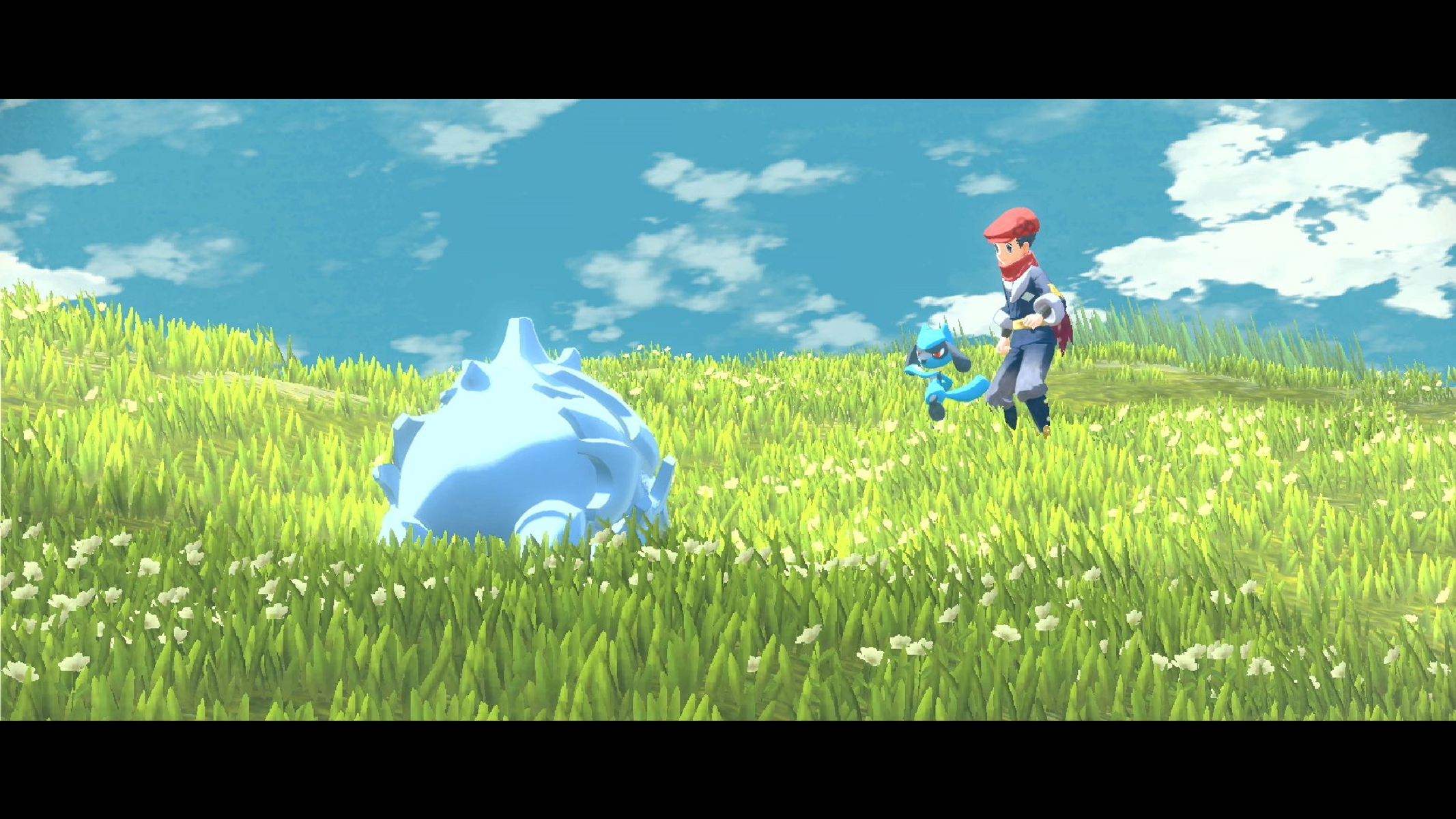 Una persona con un berretto rosso e un Pokémon blu in un campo erboso, un grande oggetto blu appuntito nelle vicinanze. Cielo blu con nuvole.