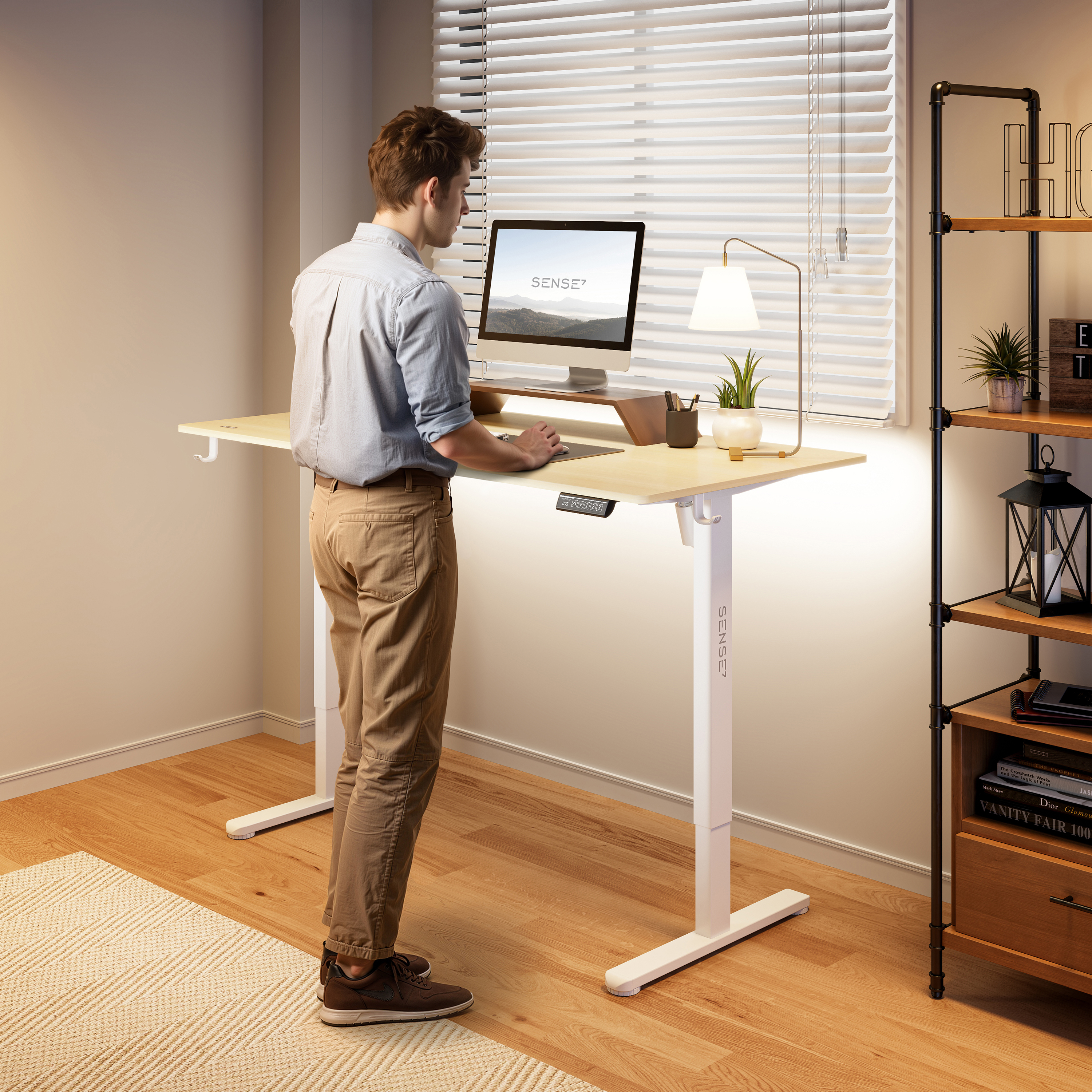 Man die aan een staande bureau staat met een computer. Bureau heeft een lamp en plant. Plankjes rechts.