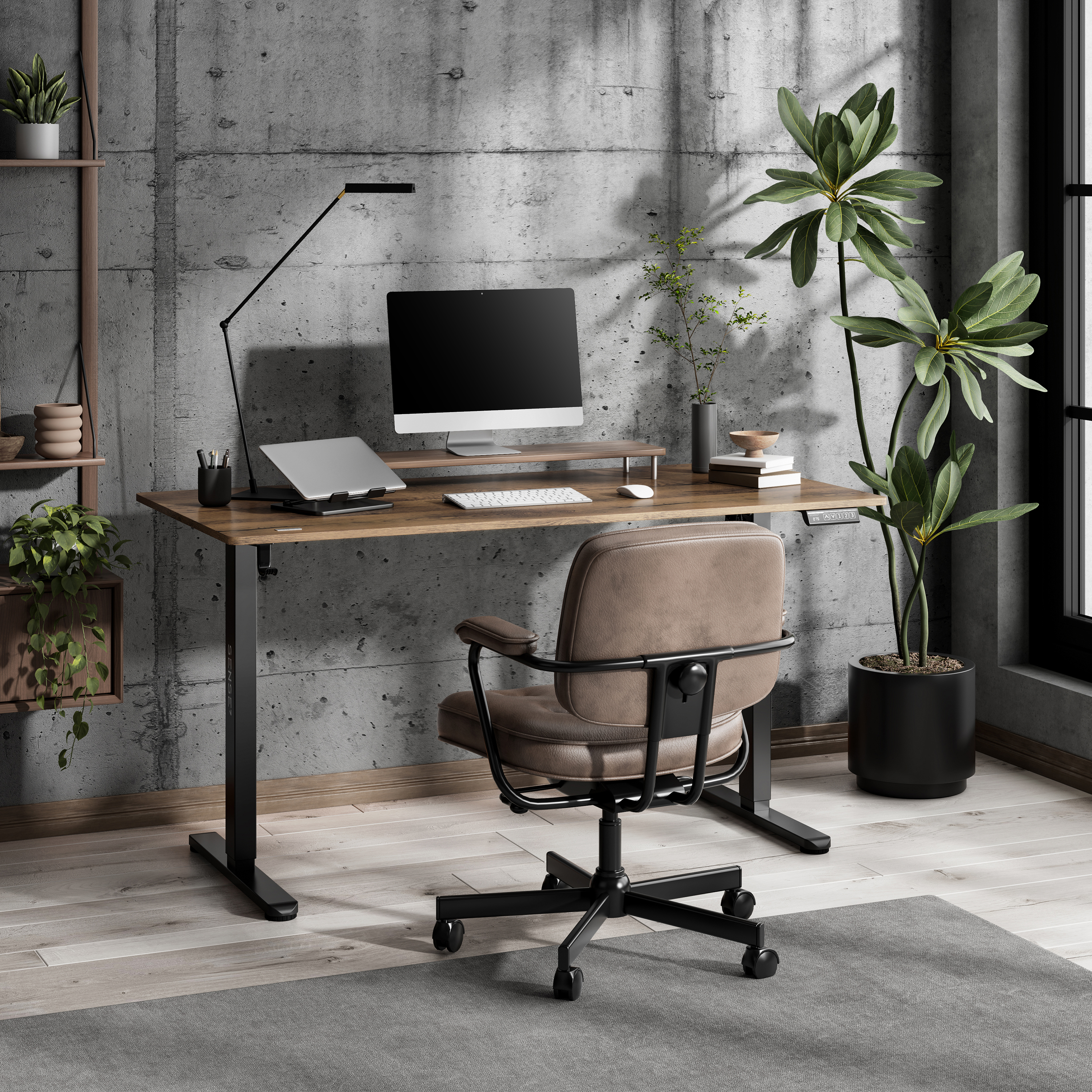 Een bureau met computer, toetsenbord en stoel. Er staan planten op de achtergrond en een betonnen muur.