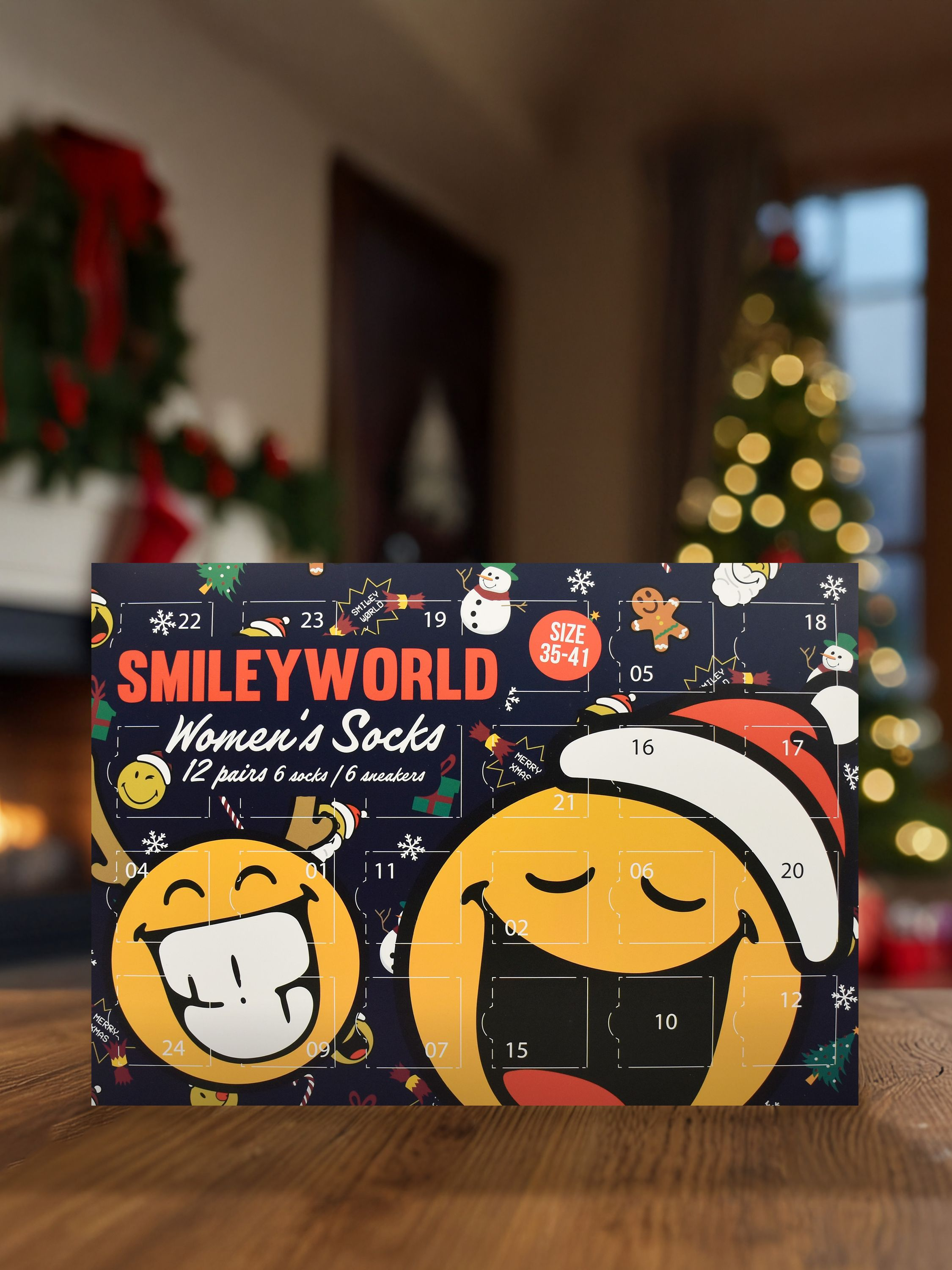 Ein SmileyWorld-Adventskalender mit Smileys, Zahlen und Weihnachtsdekorationen auf einem Holztisch mit einem Weihnachtsbaum.