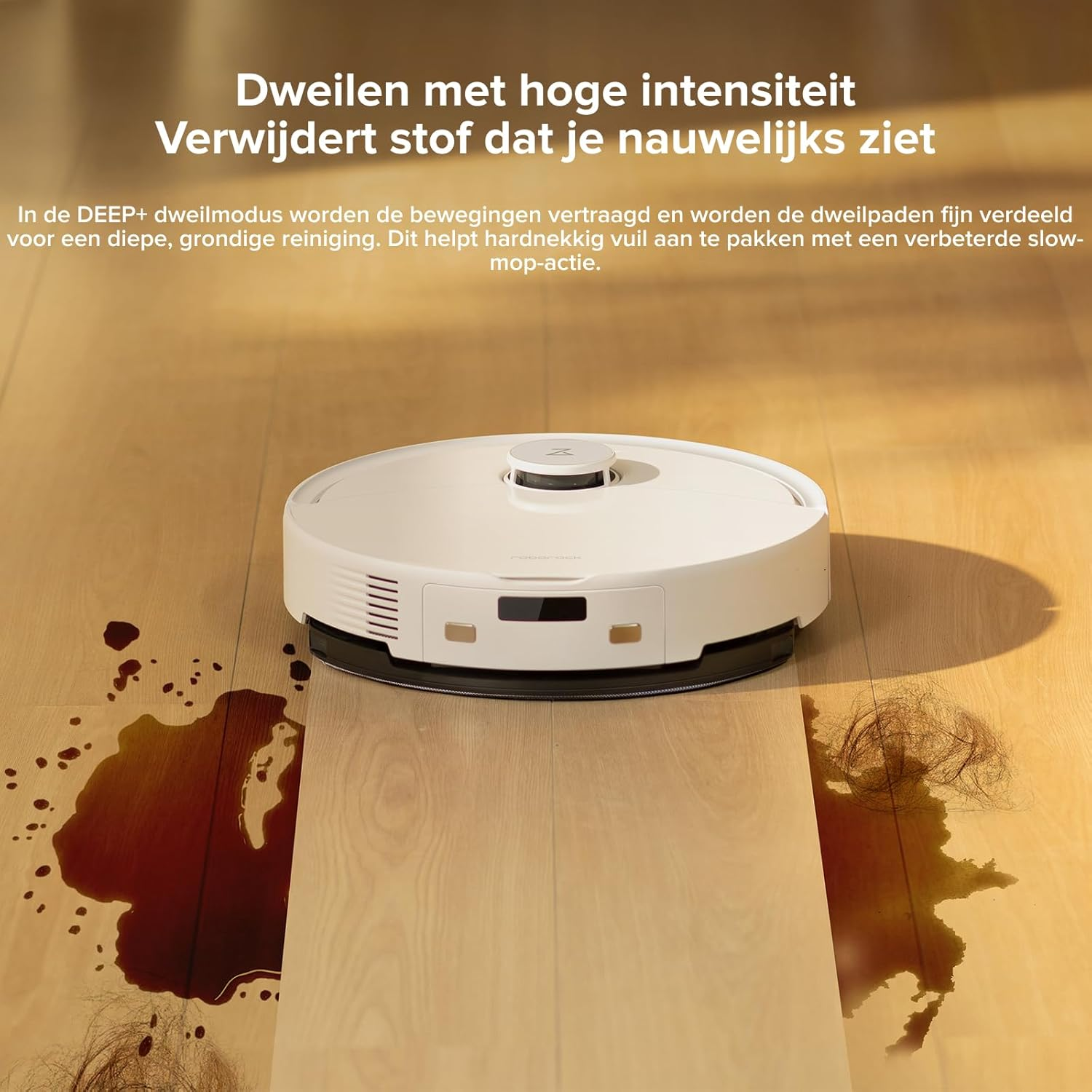 Un robot aspirateur blanc sur un sol en bois, nettoyant du liquide renversé et des cheveux. Du texte en néerlandais est visible en haut.