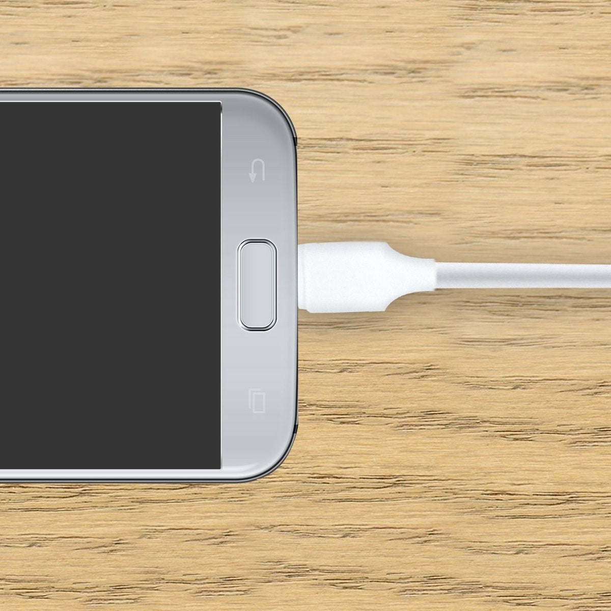 A phone partially visible, with a white charging cable plugged in. It sits on a wooden surface. The screen is black.