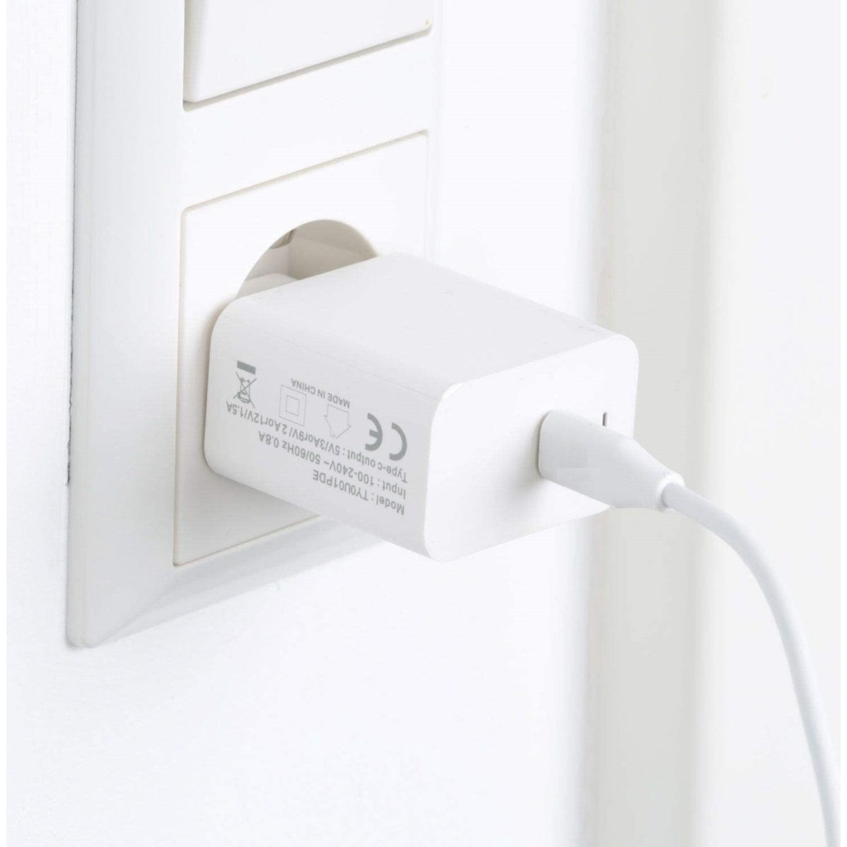 Een witte oplader is aangesloten op een wit stopcontact. De oplader heeft een USB-C-poort en een witte kabel.