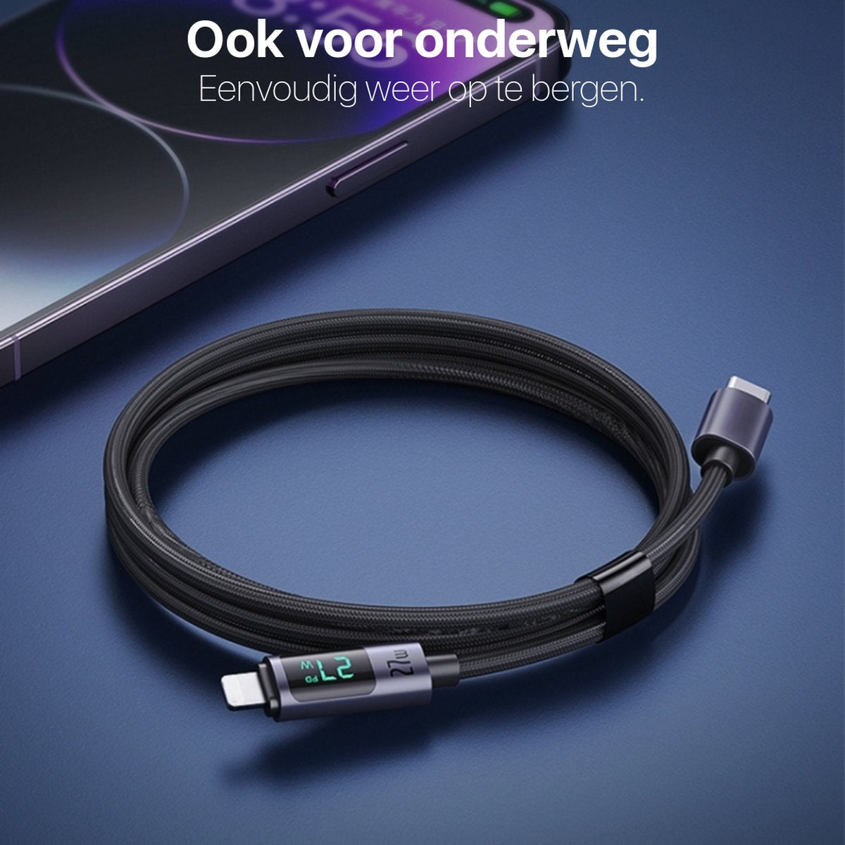Een zwarte USB-C oplaadkabel opgerold op een blauw oppervlak, met gedeeltelijk zichtbare telefoon op de achtergrond.