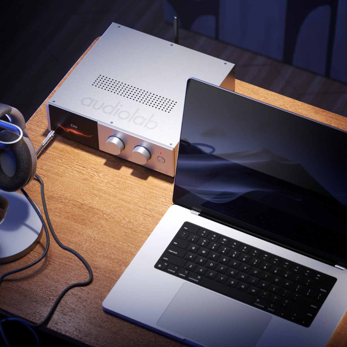 Een zilveren audioversterker, een laptop en een koptelefoon staan op een houten bureau. Het laptopscherm is donker en reflecteert de kamer.