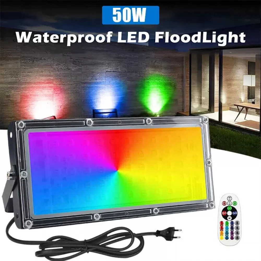 Ein mehrfarbiger LED-Flutlichtstrahler mit Fernbedienung. Der Hintergrund zeigt drei farbige Lichter und eine moderne Außenumgebung.