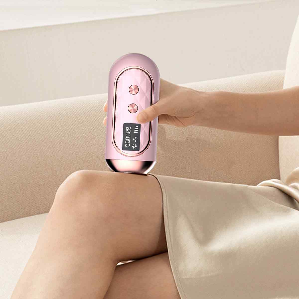 Eine Person hält ein rosa Gerät auf dem Knie. Das Gerät hat einen Bildschirm und Knöpfe. Sie sitzt auf einem beigen Sofa.