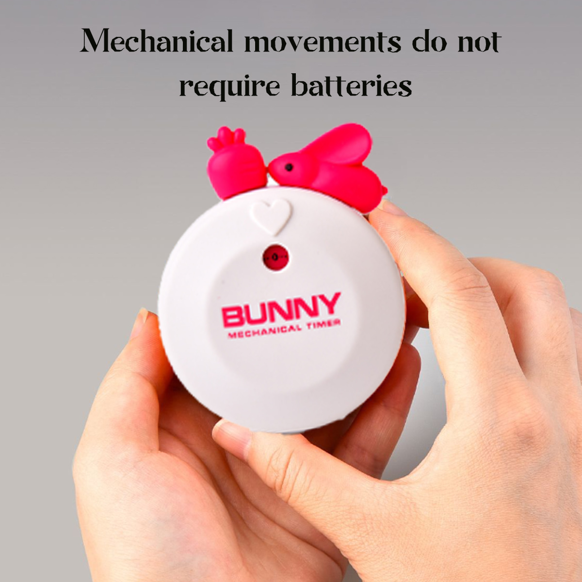 Weißer mechanischer Bunny-Timer in Händen gehalten. Oben ist ein rosa Hase. Text: Mechanische Bewegungen benötigen keine Batterien.