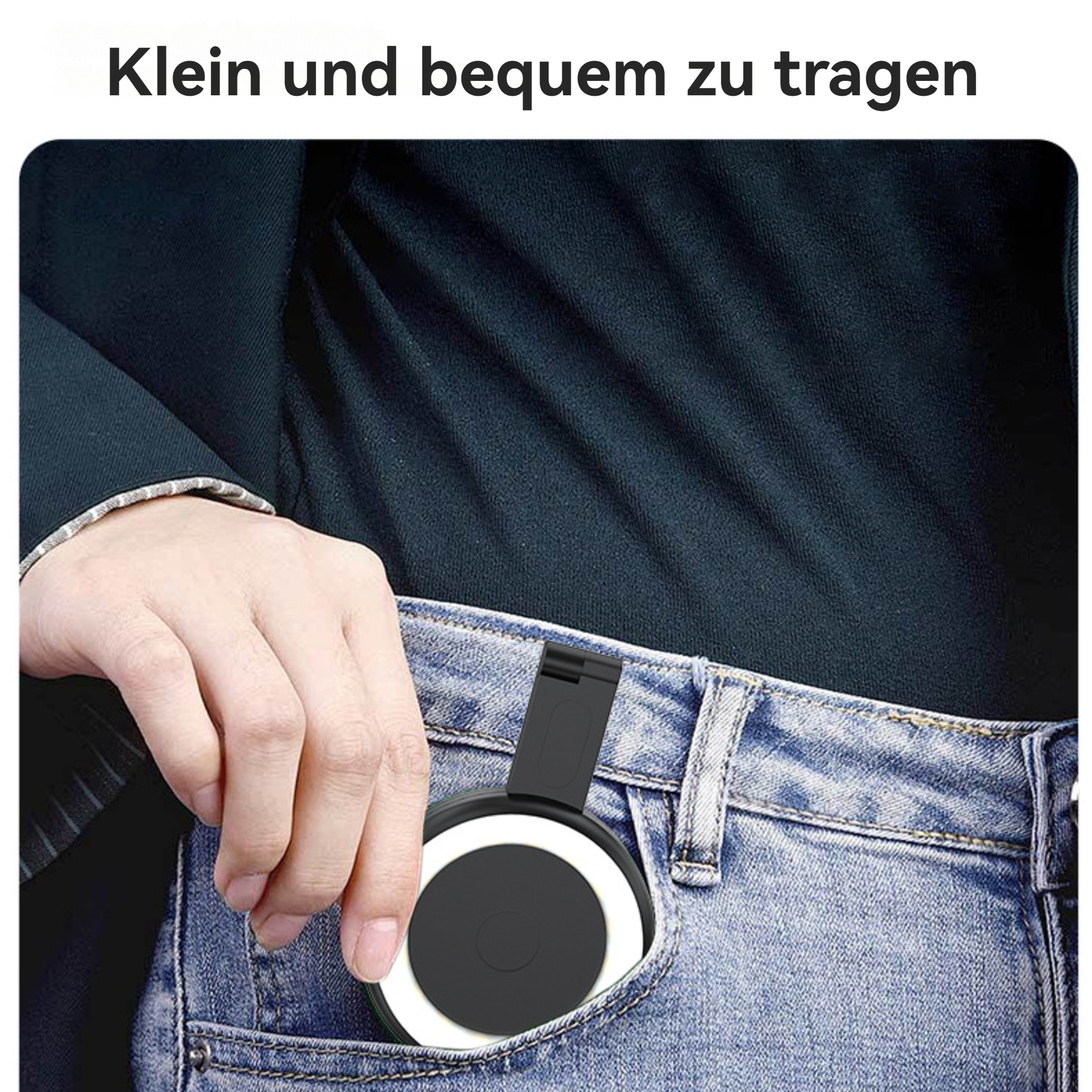 Eine Hand hält ein schwarz-weißes Gerät in einer Jeans-Tasche. Die Person trägt ein marineblaues Hemd.