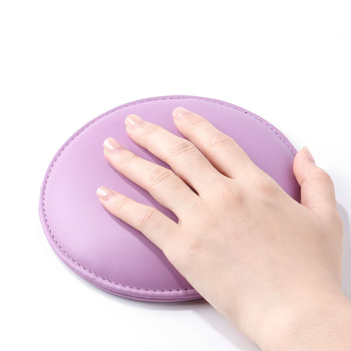 Eine Hand liegt auf einem ovalen, lavendelfarbenen Pad. Das Pad liegt auf einer weißen Oberfläche. Die Hand hat kurze Nägel. Der Hintergrund ist weiß.