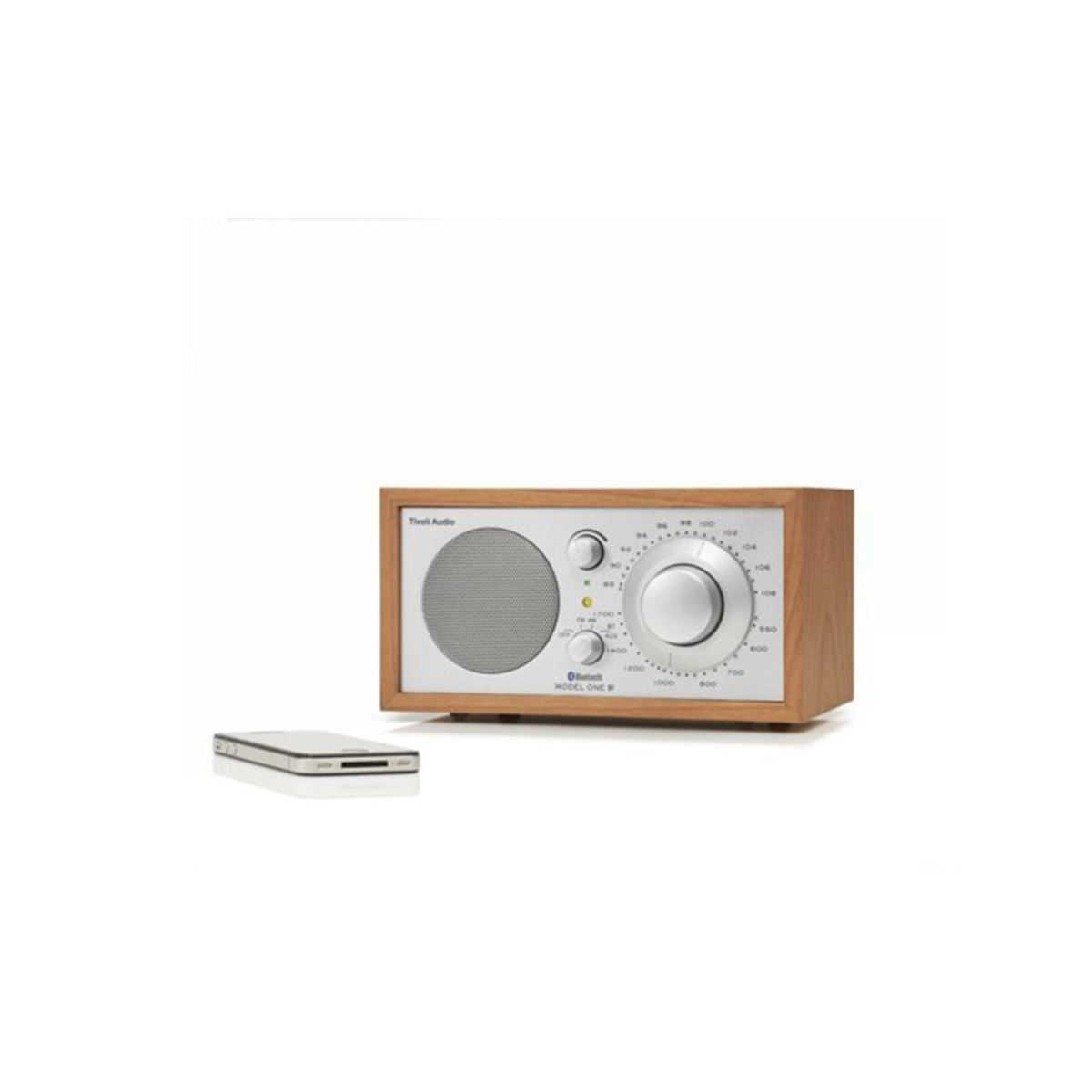 Ein Holzradio mit silberner Front und einem kleinen Telefon daneben. Das Radio hat einen Lautsprecher, ein Zifferblatt und Knöpfe.