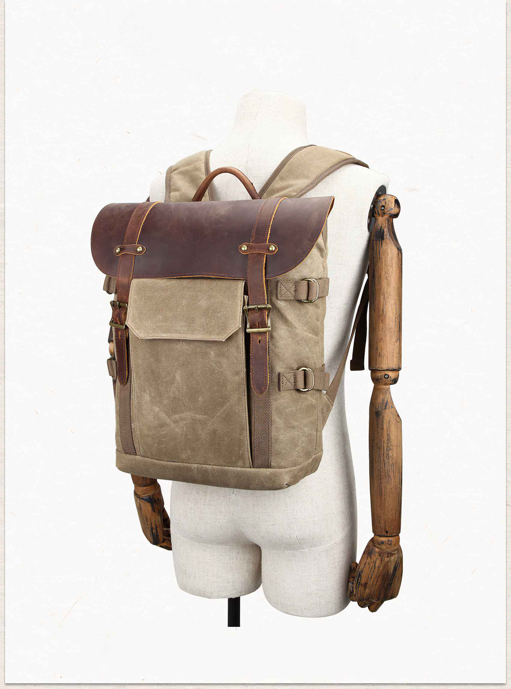 Ein Rucksack aus Segeltuch mit Lederakzenten wird auf einer Schaufensterpuppe präsentiert. Die Tasche ist olivgrün mit braunen Lederriemen.