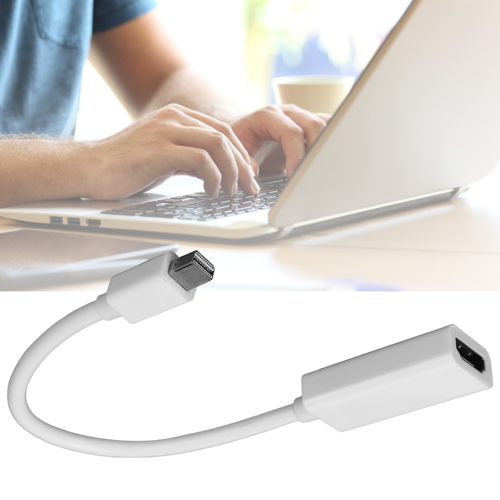 Eine Person tippt auf einem Laptop. Ein weißes HDMI-Adapterkabel befindet sich im Vordergrund. Kaffeetasse im Hintergrund sichtbar.