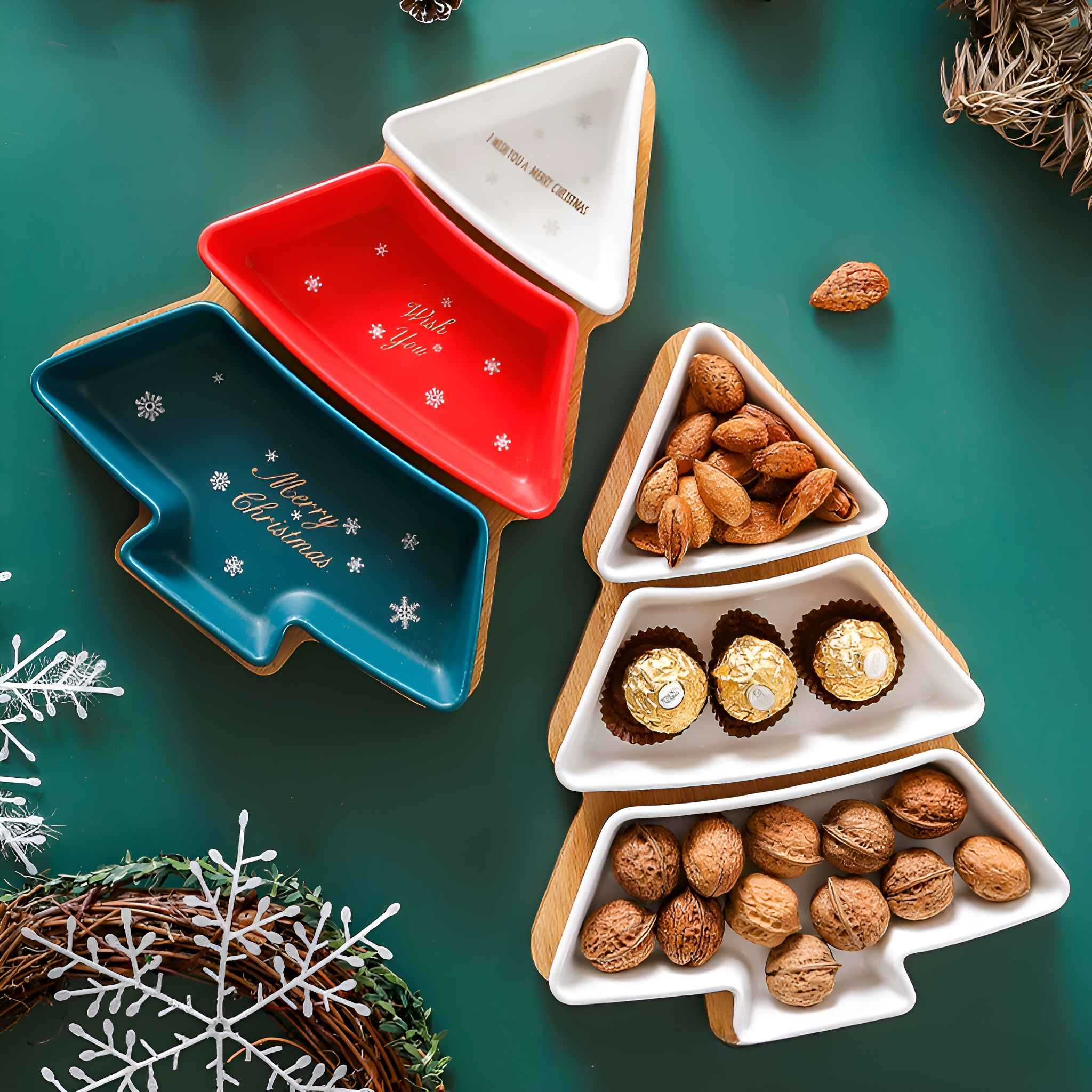 Weihnachtsbaumförmige Servierschalen mit Nüssen, Pralinen und festlichem Text auf grünem Hintergrund. Dekorationen wie Schneeflocken.
