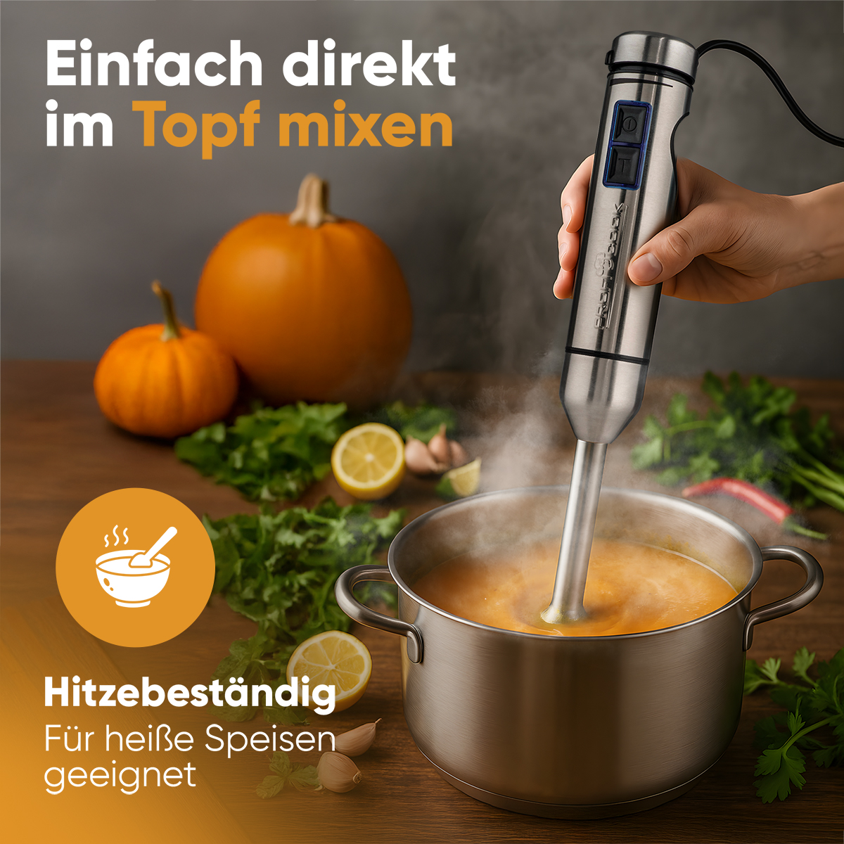 Una mano tiene un frullatore a immersione e mescola la zuppa in una pentola. Zucca, limoni ed erbe aromatiche sul tavolo di legno.