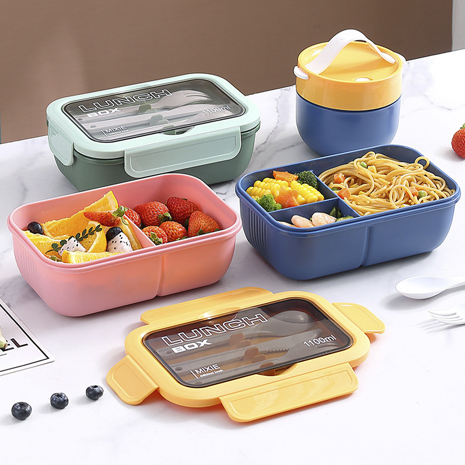 Diverse scatole per il pranzo con cibo, tra cui frutta, pasta e verdure. Le scatole sono di vari colori: rosa, blu, verde e giallo.