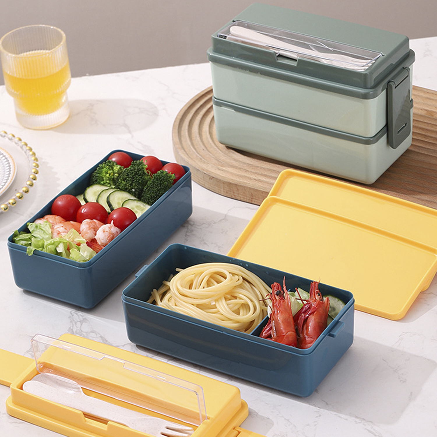 Varios tuppers con comida: pasta, camarones, tomates, brócoli y lechuga. También se ve un vaso de zumo y cubiertos.