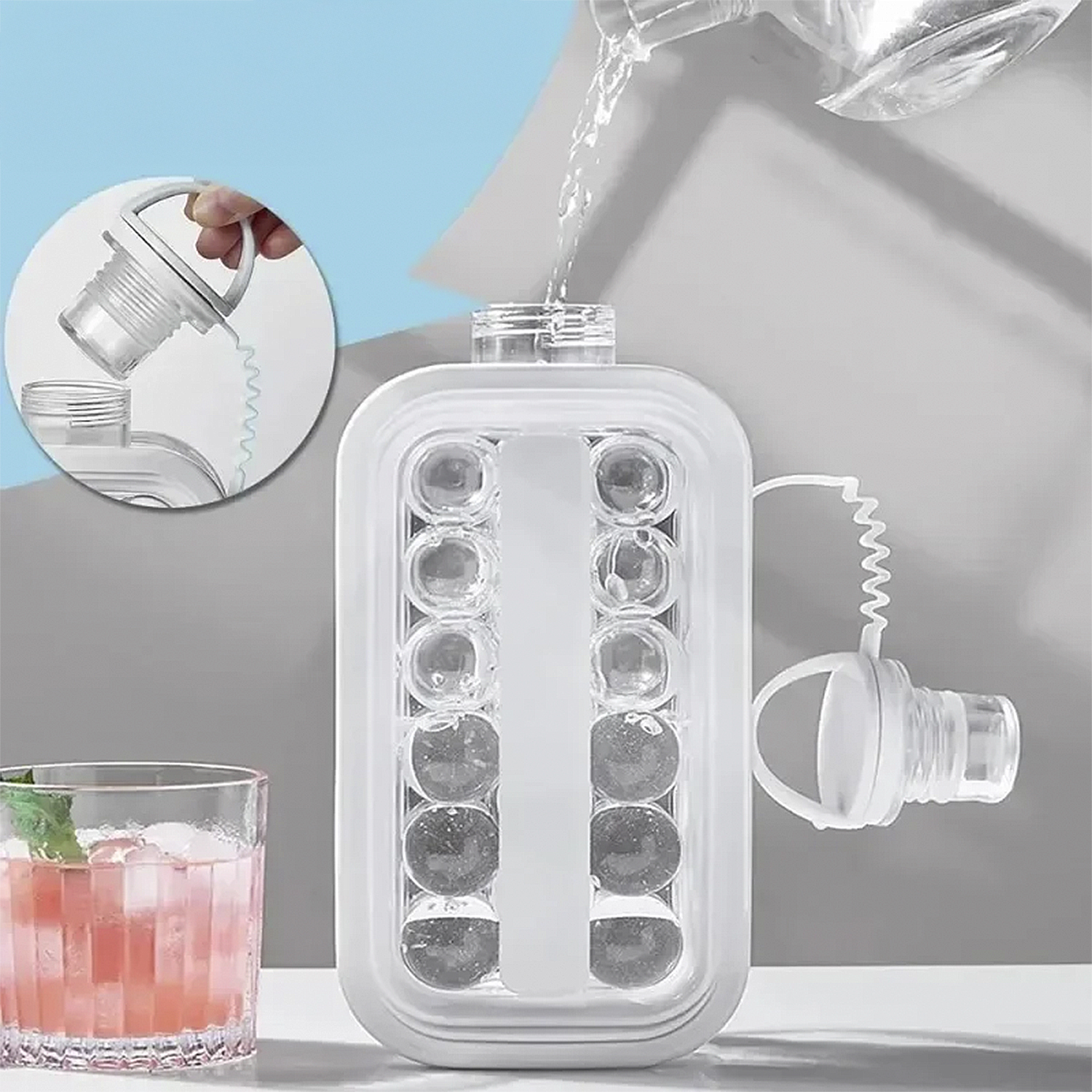 Uno stampo per ghiaccio trasparente viene riempito con acqua. Sono visibili anche un bicchiere di bevanda rosa con menta e un tappo.