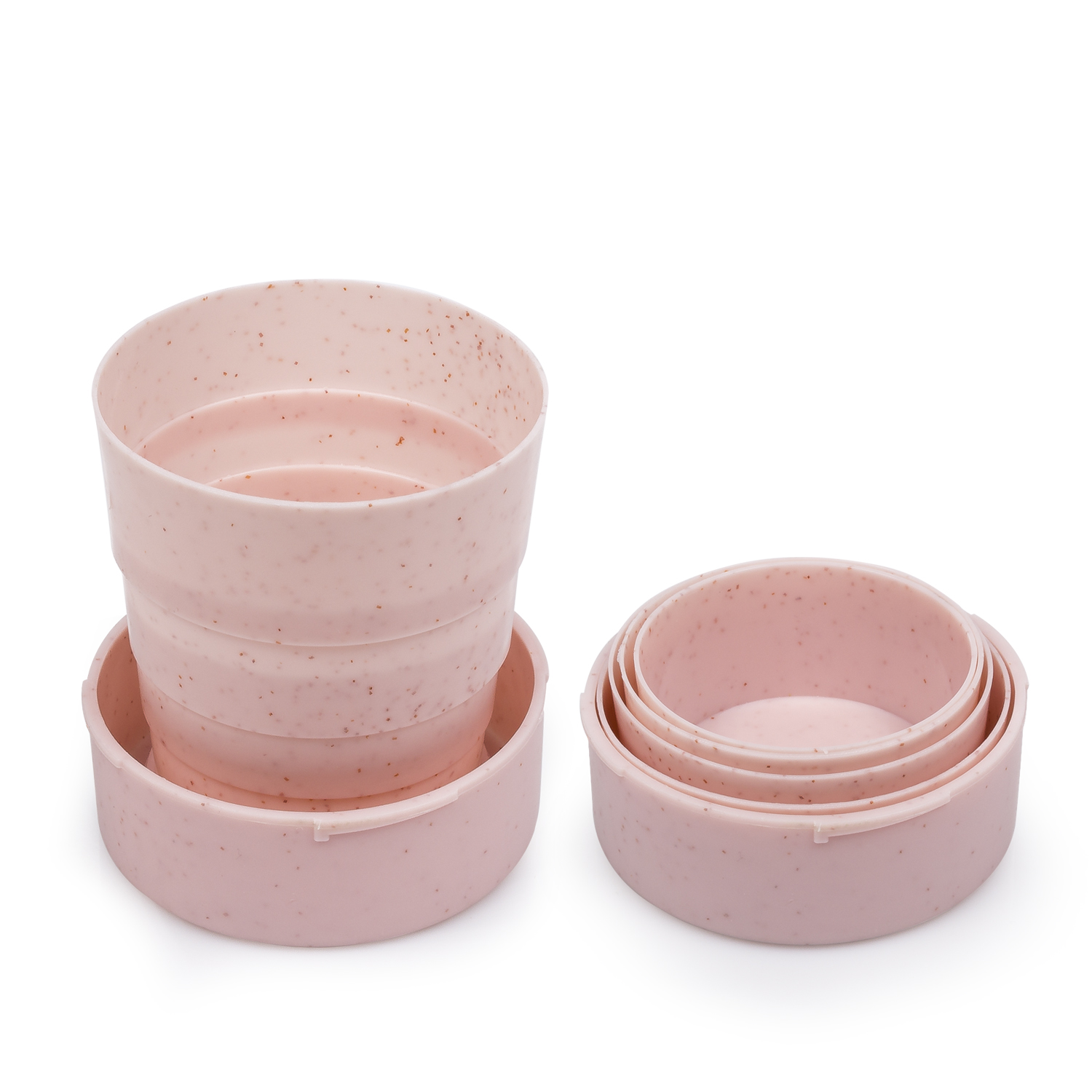 Tazza rosa pieghevole con coperchio e due ciotole nidificate. La tazza è parzialmente piegata. Tutti gli oggetti hanno una texture maculata.