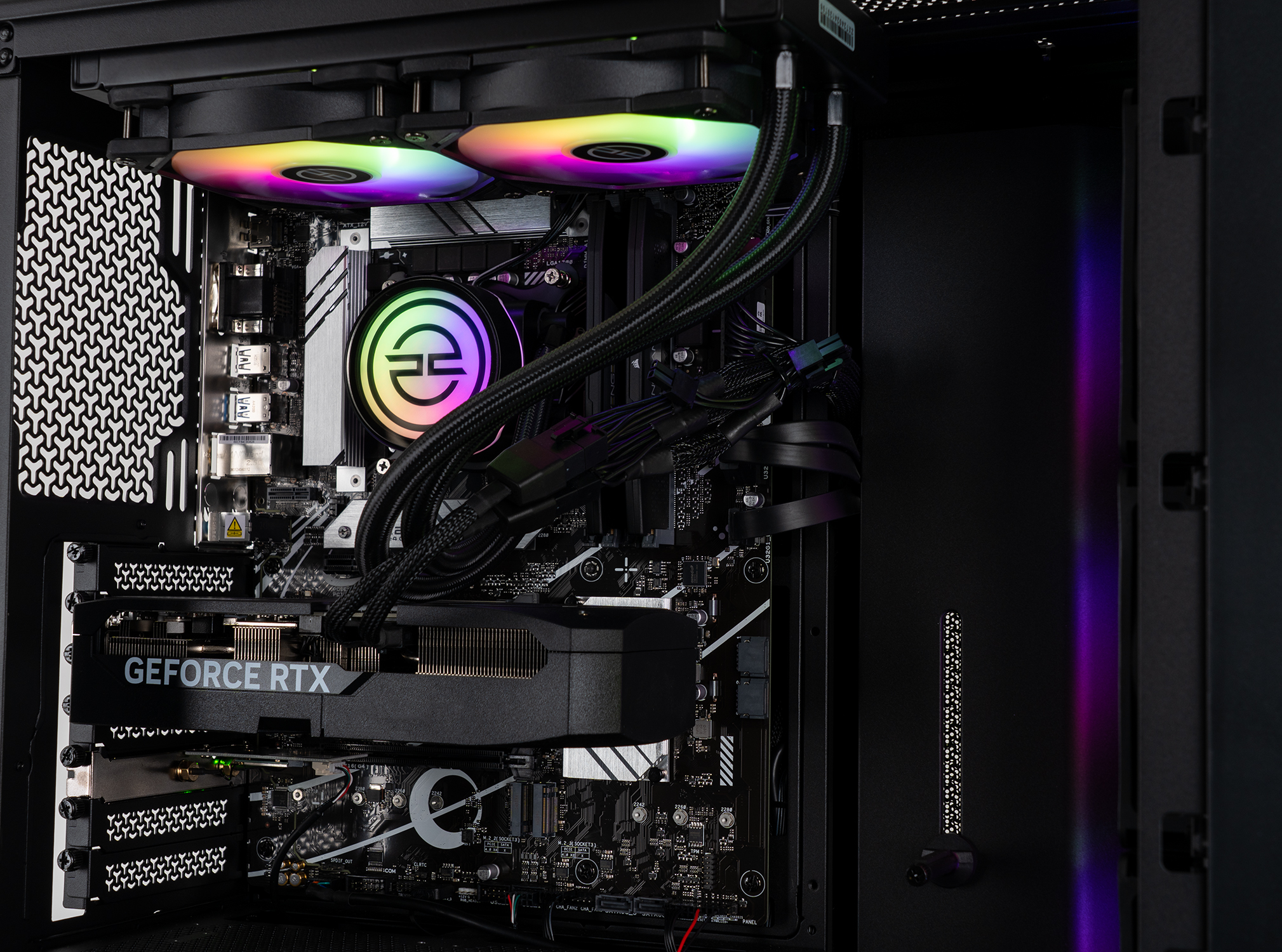 Interno di un case di computer con componenti, tra cui una scheda grafica, ventole e scheda madre, illuminato da LED colorati.