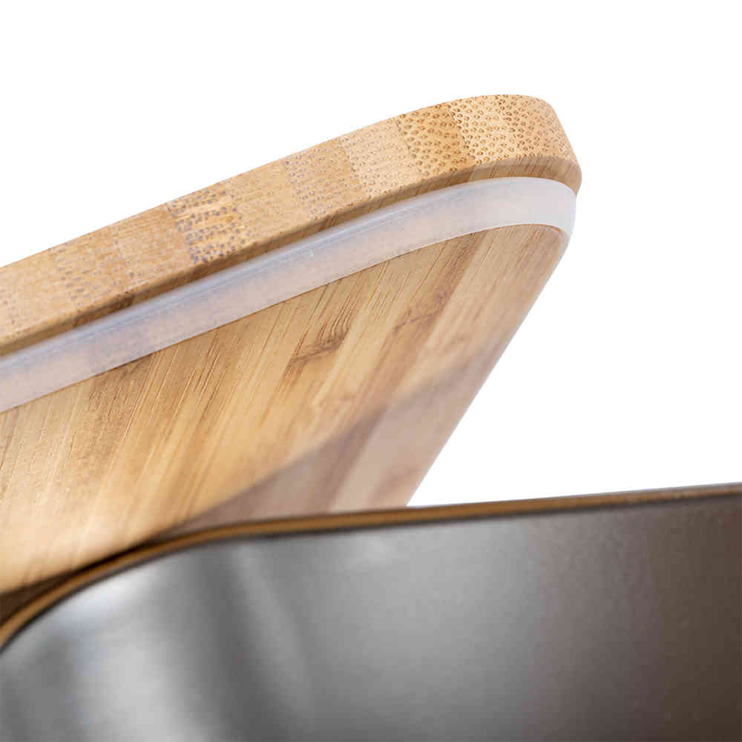 Una tabla de cortar de madera con un borde de silicona blanco y un recipiente de metal oscuro debajo. Aislado sobre un fondo blanco.