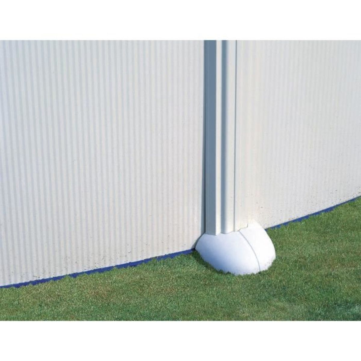 Una sección blanca y ondulada de la pared de la piscina con un poste de soporte, que descansa sobre una base blanca y césped verde. Una línea azul marca el borde.