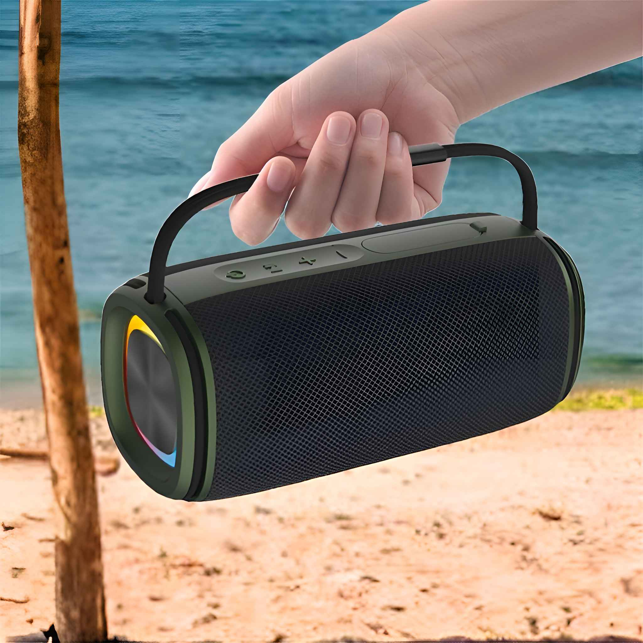 Eine Hand hält einen schwarzen Lautsprecher mit Griff. Der Lautsprecher hat eine Netzfront. Strand und Meer sind im Hintergrund.
