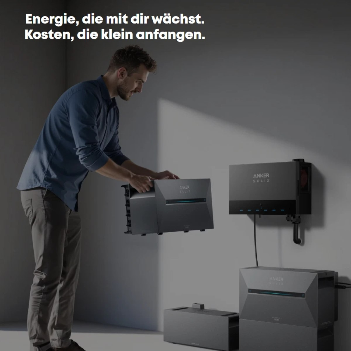 Ein Mann installiert Solarmodule. Die Szene umfasst graue Solarmodule an einer grauen Wand, mit sichtbarem Markennamen.