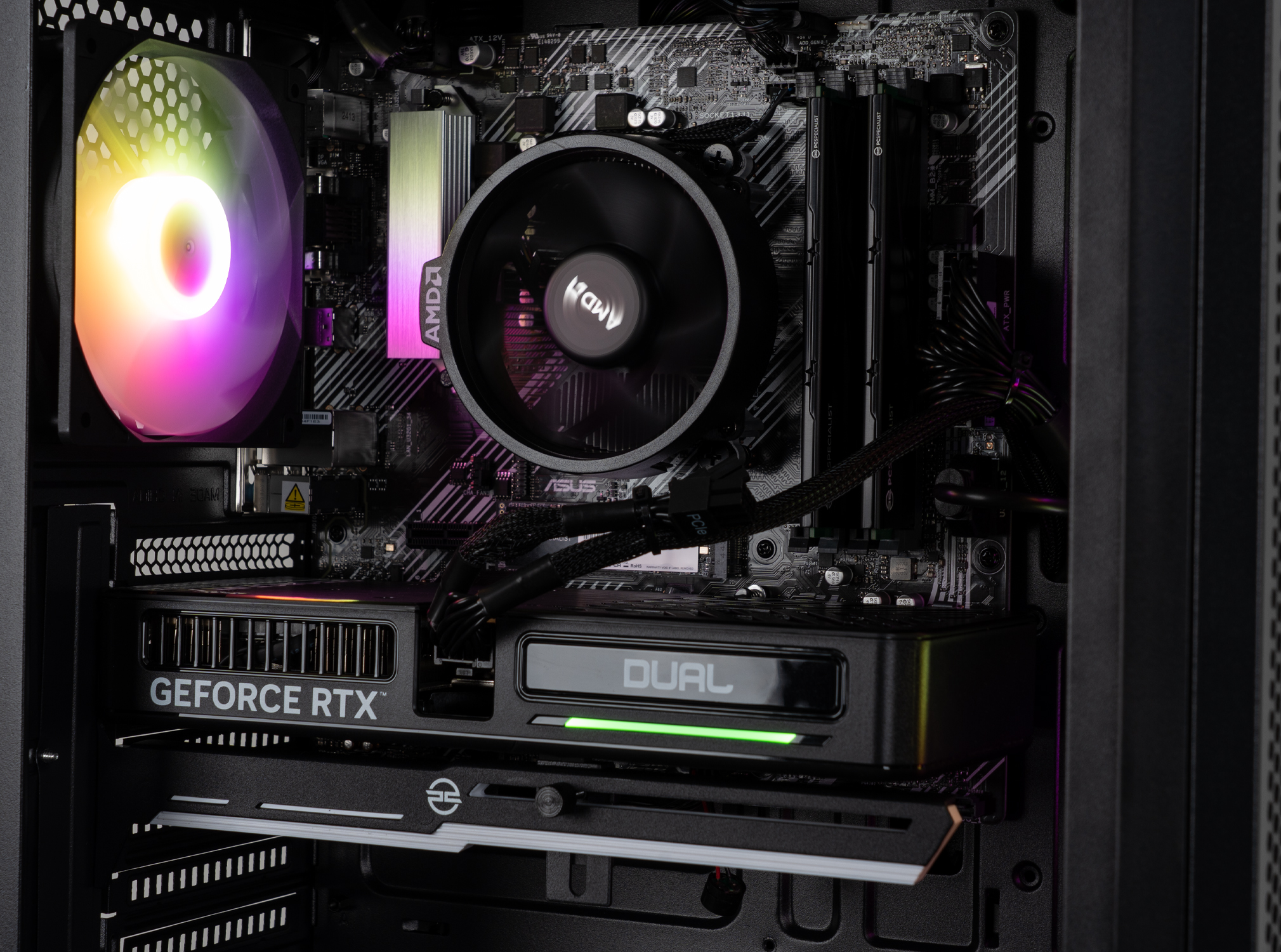 All'interno di un case di computer, sono visibili una scheda grafica e un dissipatore della CPU. La scheda dice 'GEFORCE RTX'. Una ventola si illumina con più colori.
