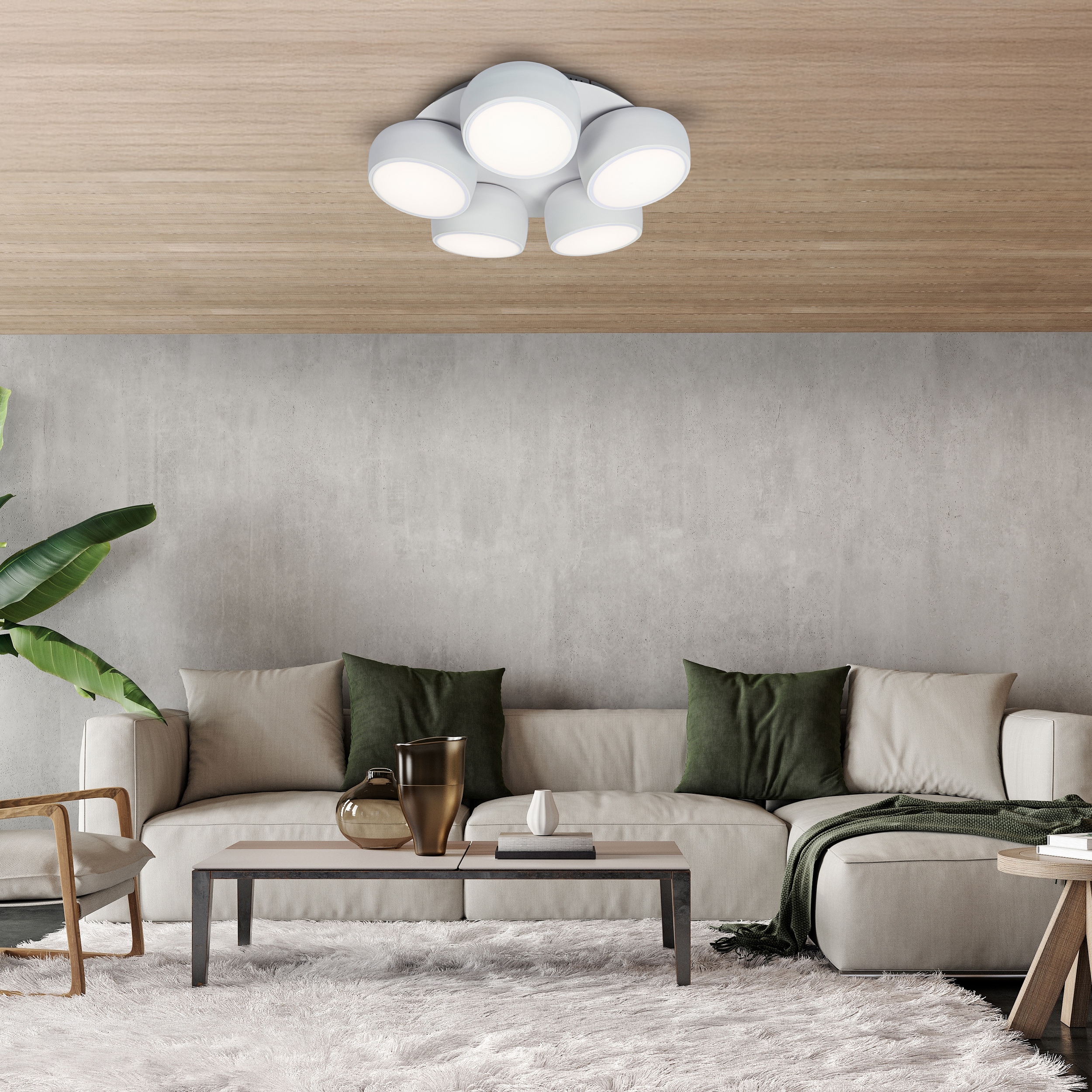 Ein modernes Wohnzimmer mit beigem Sofa, grünen Kissen, Couchtisch, Deckenleuchte und flauschigem Teppich.