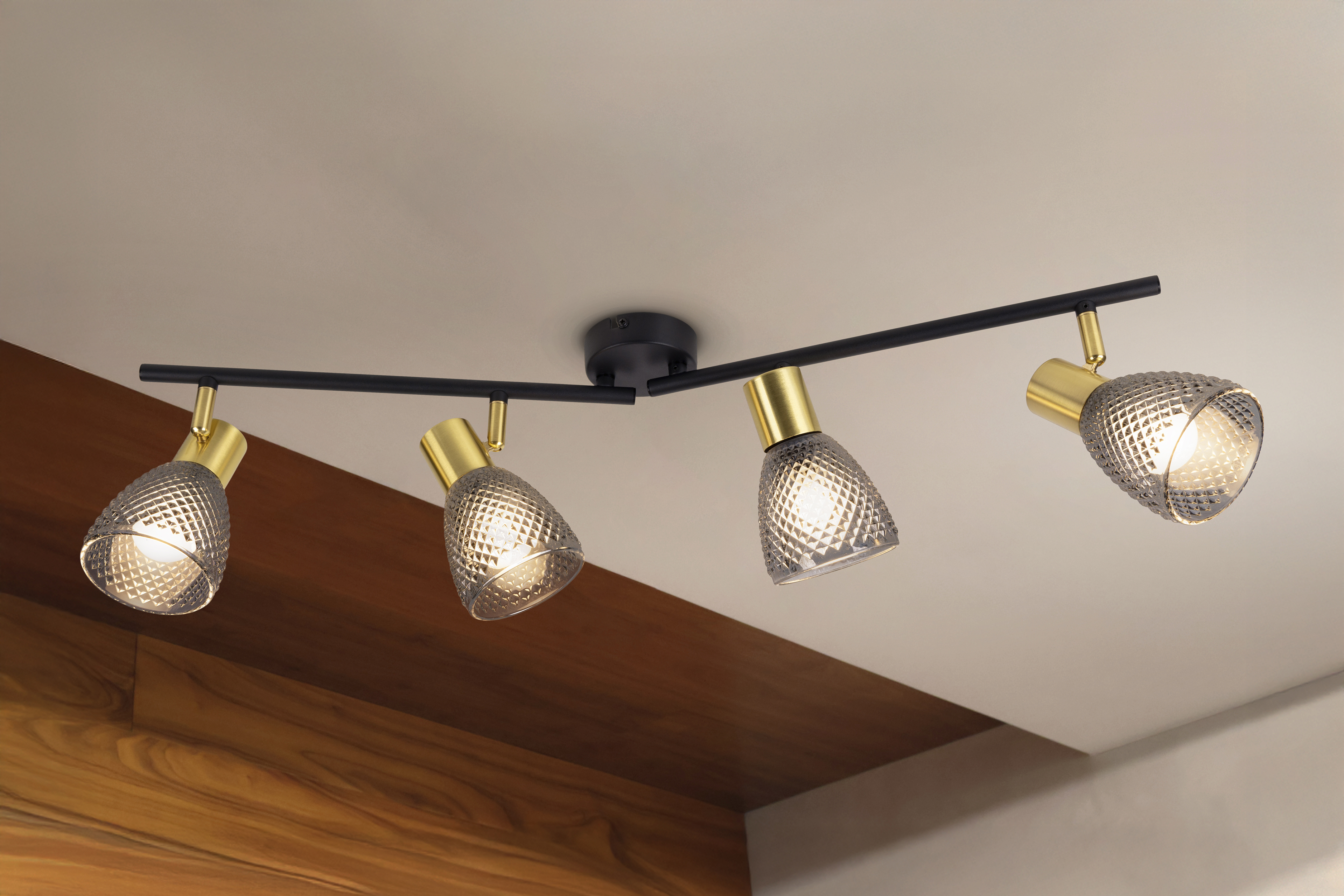 Vier moderne Schienenleuchten hängen von der Decke. Jede Leuchte hat einen goldenen Sockel und einen gemusterten Glasschirm.
