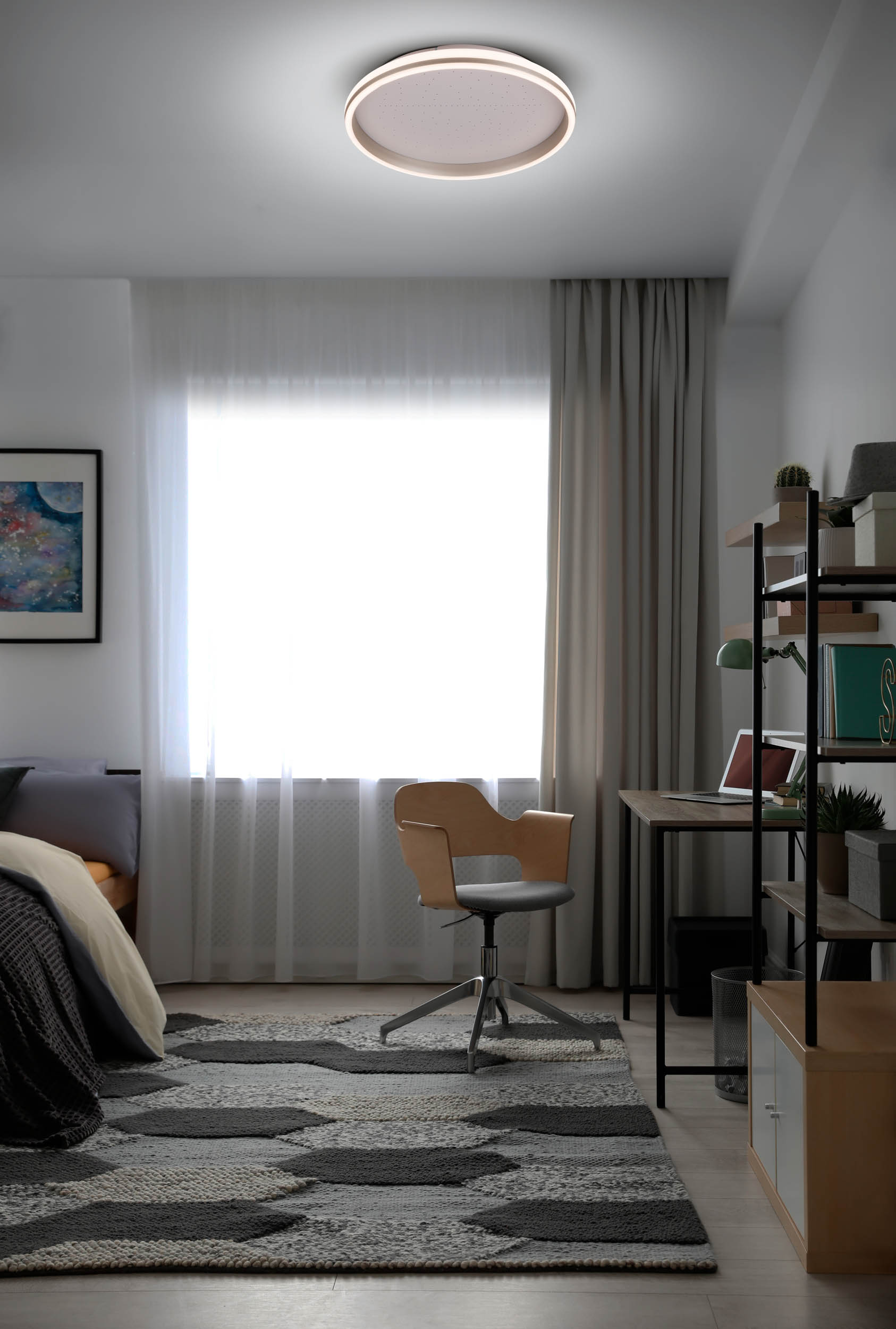 Schlafzimmer mit Teppich, Schreibtisch und Stuhl. Ein großes Fenster und ein Bett sind ebenfalls sichtbar. Eine runde Deckenleuchte ist vorhanden.