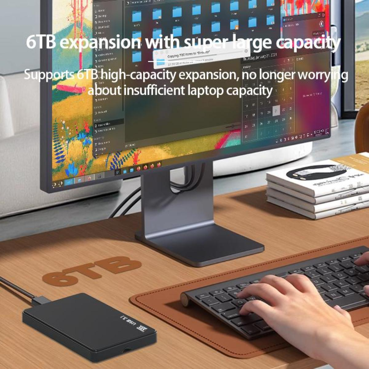 Ein Schreibtisch mit Monitor, Tastatur und externer Festplatte. Hände tippen auf der Tastatur. Text auf dem Bildschirm lautet '6TB expansion'.