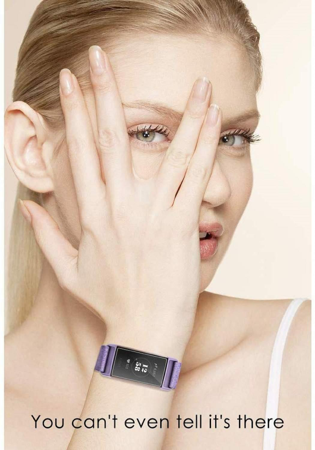 Eine Frau mit blonden Haaren bedeckt ihr Gesicht mit einer Hand. Sie trägt eine lila Smartwatch. Der Text lautet: "Man sieht es kaum". 